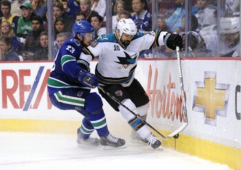 VANCOUVER, CANADA - MAY 24:  Jamal Mayers #10 of the San Jose Sharks moves the puck along the end boards against the San Jose Sharks Alexander Edler #23 of the Vancouver Canucks defends the play in Game Five of the Western Conference Finals during the 201