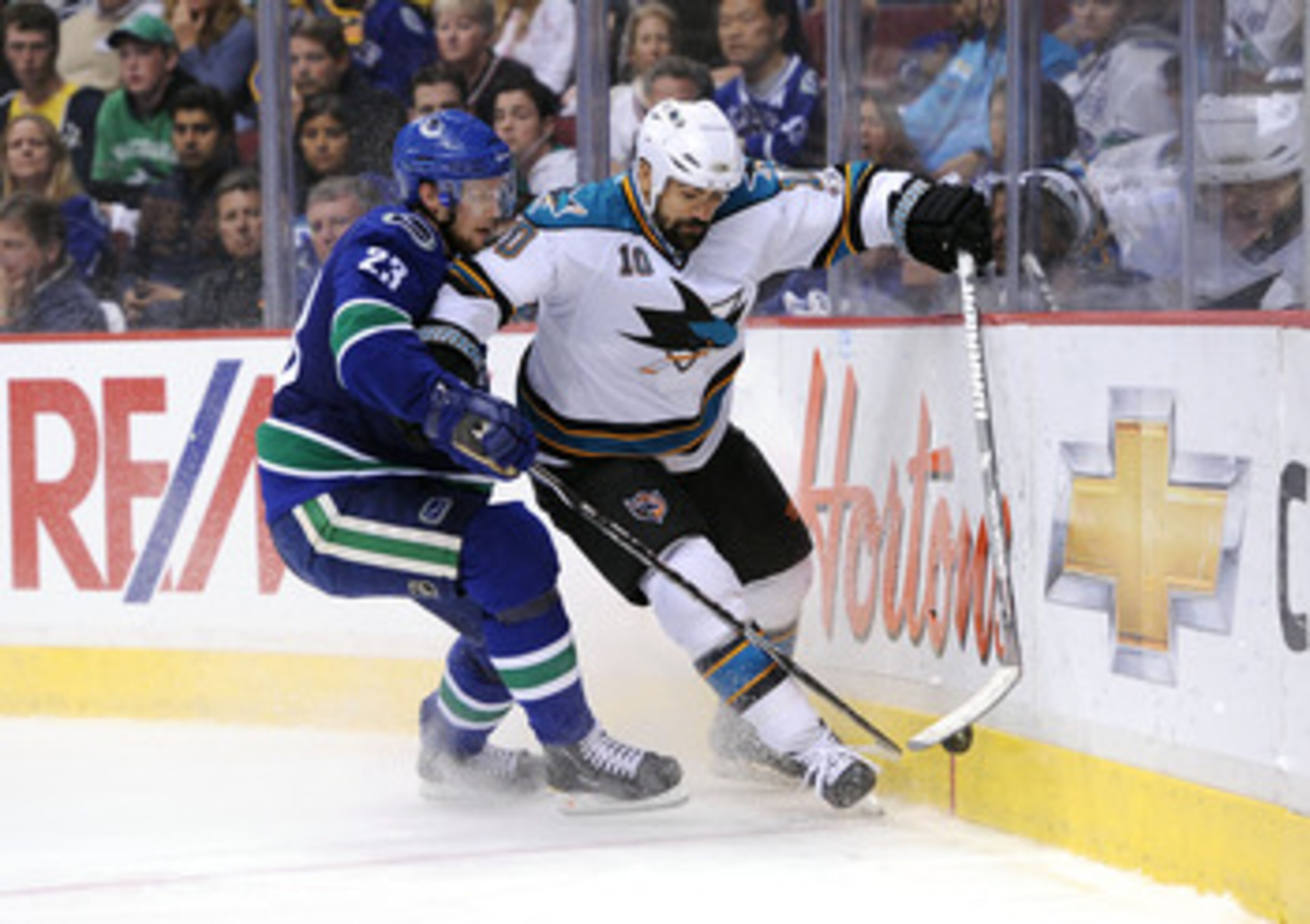 VANCOUVER, CANADA - MAY 24:  Jamal Mayers #10 of the San Jose Sharks moves the puck along the end boards against the San Jose Sharks Alexander Edler #23 of the Vancouver Canucks defends the play in Game Five of the Western Conference Finals during the 201