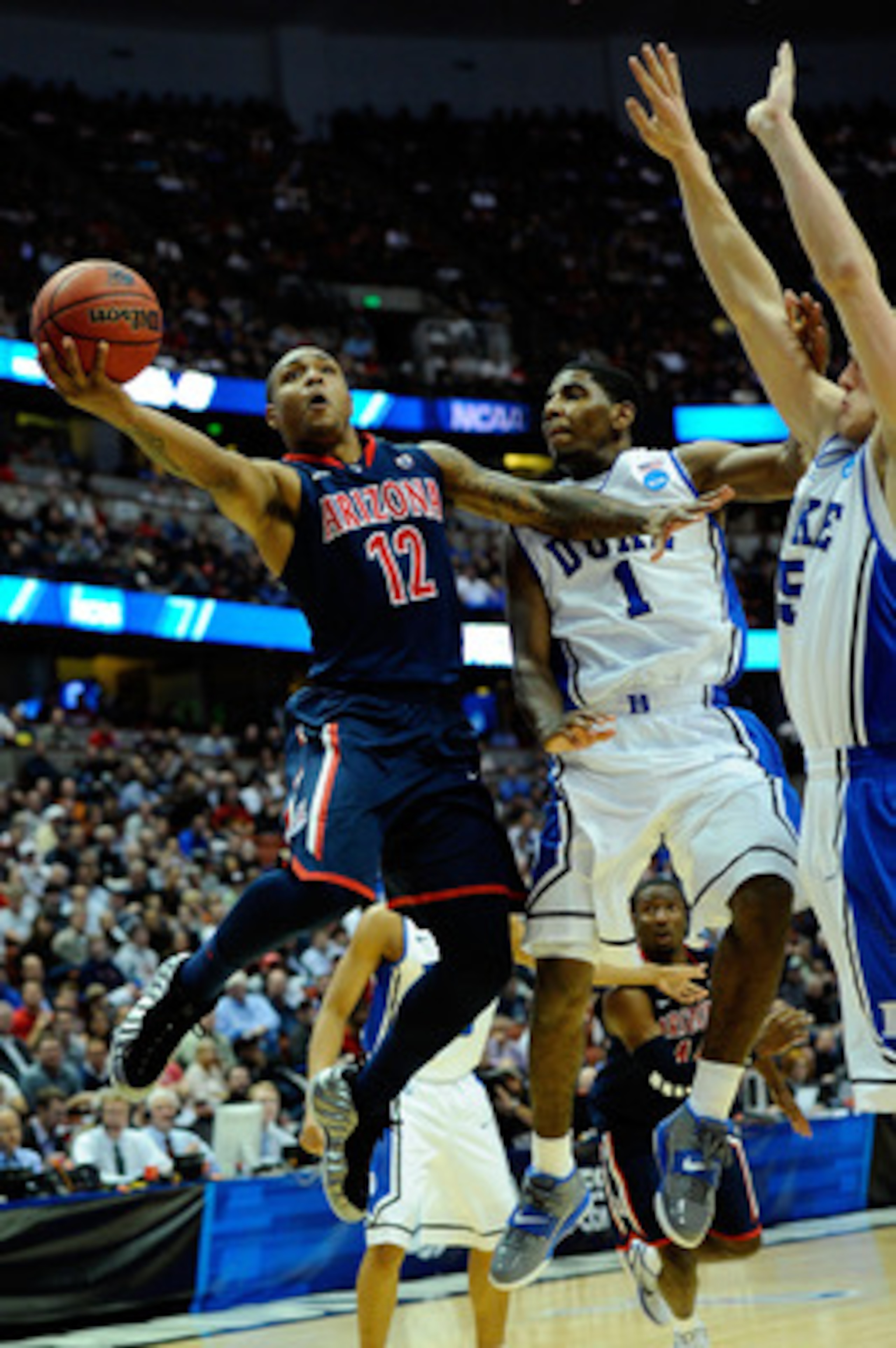 ANAHEIM, CA - MARCH 24:  Lamont Jones #12 of the Arizona Wildcats goes to the hoop against Kyrie Irving #1 and Mason Plumlee #5 of the Duke Blue Devils during the west regional semifinal of the 2011 NCAA men's basketball tournament at the Honda Center on