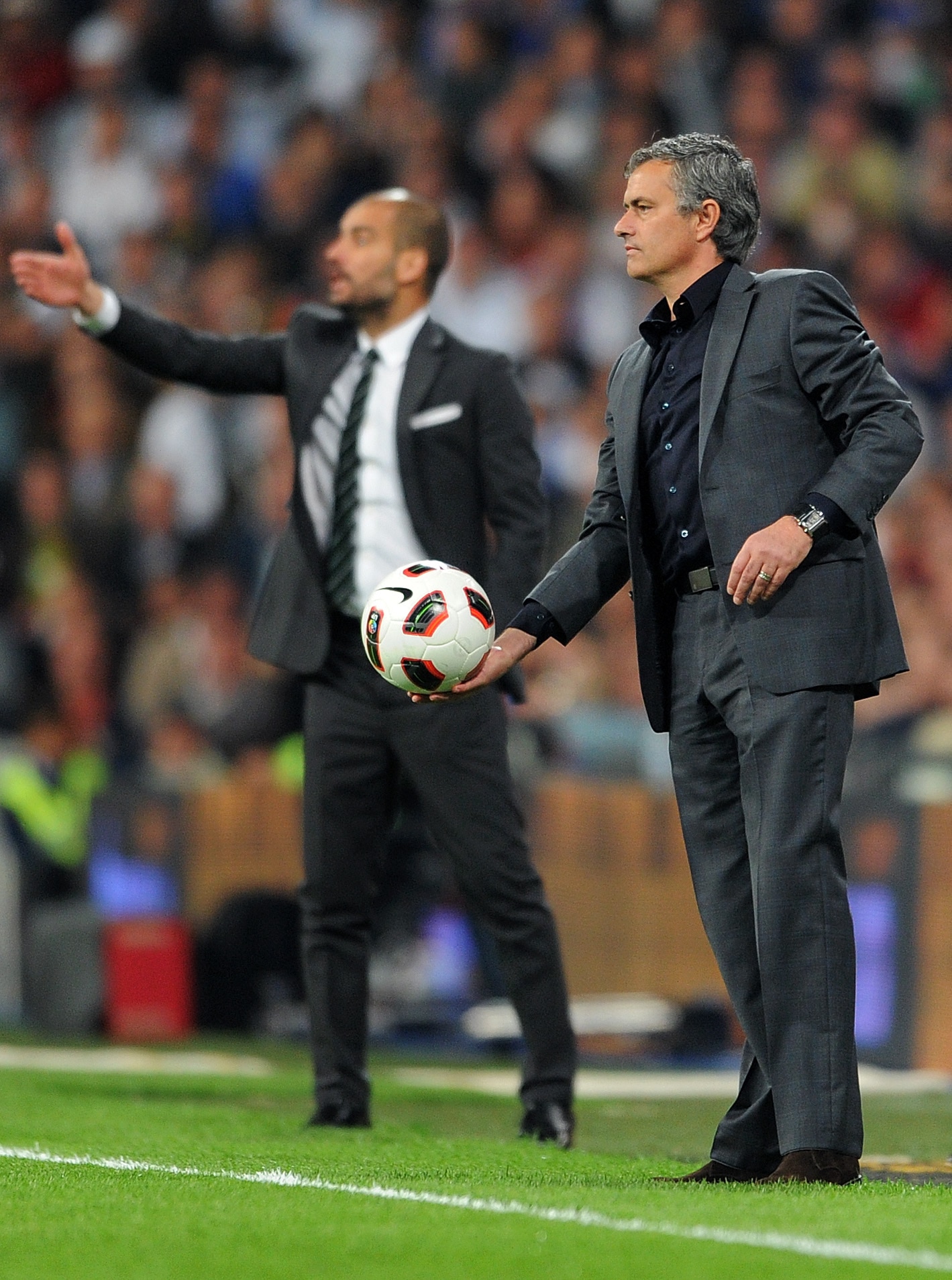 MADRID, SPAIN - APRIL 16:  Head coach Jose Mourinho (R) of Real Madrid throws the ball backdropped by head coach Josep Guardiola of Barcelona during the la Liga match between Real Madrid and Barcelona at Estadio Santiago Bernabeu on April 16, 2011 in Madr