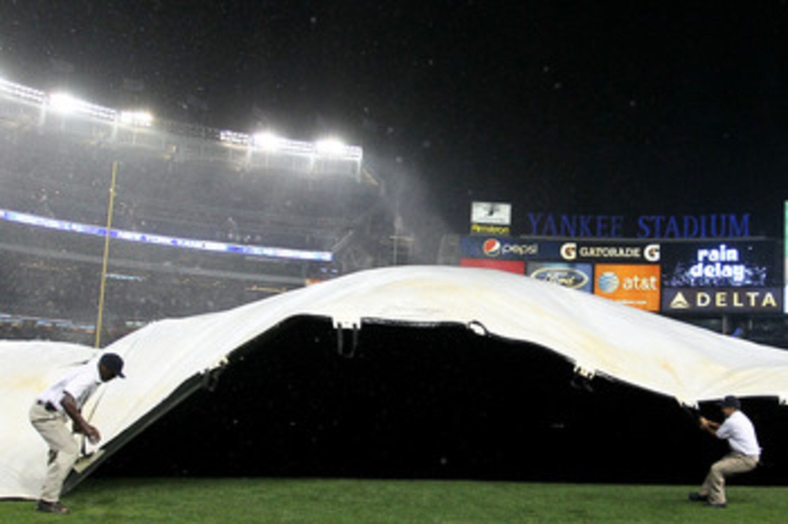 NEW YORK - SEPTEMBER 22:  New York Yankees grounds staff pull over the covers as heavy rains and high winds delayed the game between the New York Yankees and the Tampa Bay Rays during their game on September 22, 2010 at Yankee Stadium in the Bronx borough