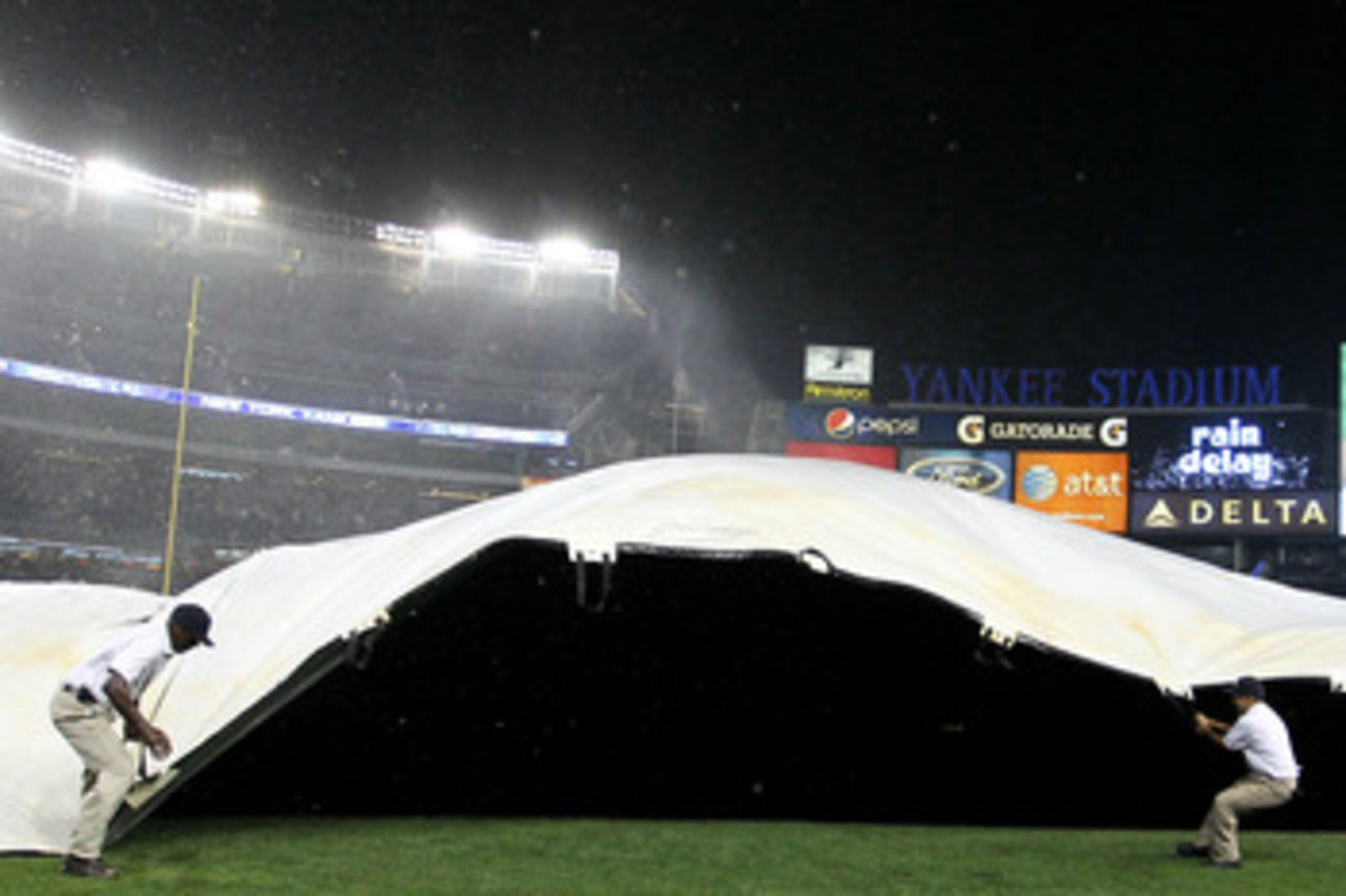NEW YORK - SEPTEMBER 22:  New York Yankees grounds staff pull over the covers as heavy rains and high winds delayed the game between the New York Yankees and the Tampa Bay Rays during their game on September 22, 2010 at Yankee Stadium in the Bronx borough