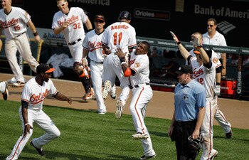 BALTIMORE, MD - MAY 26: Robert Andino #11 of the Baltimore Orioles jumps into the arms of teammate Adam Jones #10 (R) after Andino scored the game winning run to defeat the Kansas City Royals 6-5 in twelve innings at Oriole Park at Camden Yards on May 26,