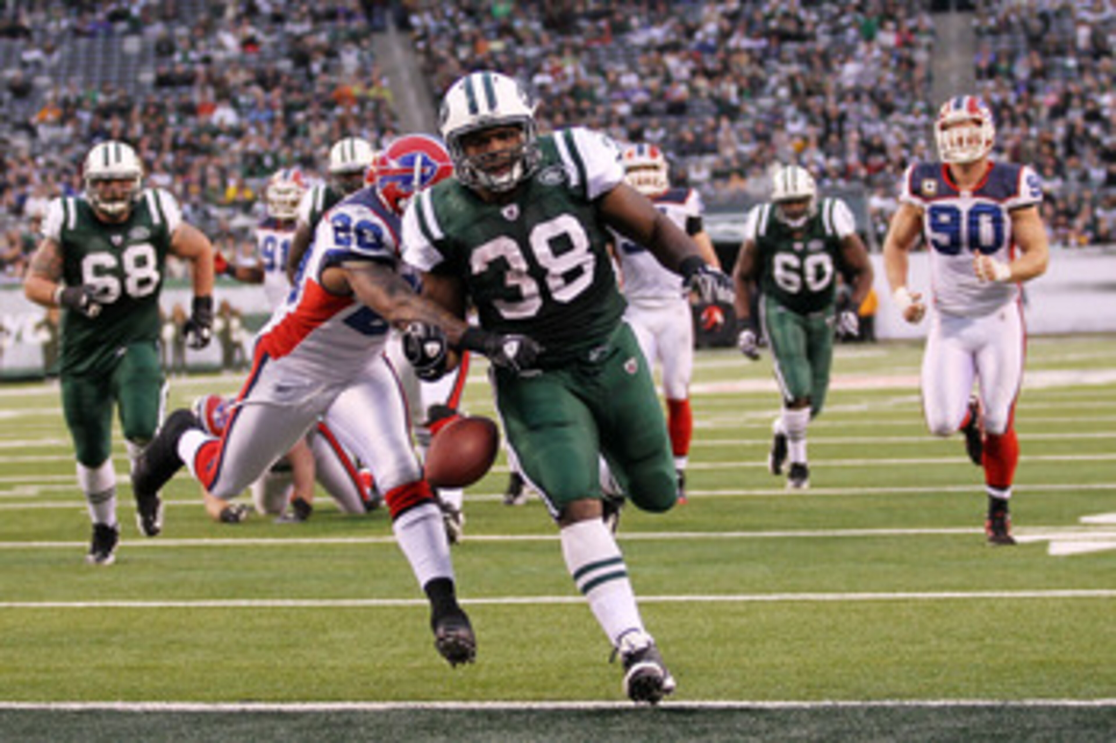 EAST RUTHERFORD, NJ - JANUARY 02:  John Conner #38 of the New York Jets looses the ball after scoring a touchdown against the defense of Donte Whitner #20 of the Buffalo Bills at New Meadowlands Stadium on January 2, 2011 in East Rutherford, New Jersey.  