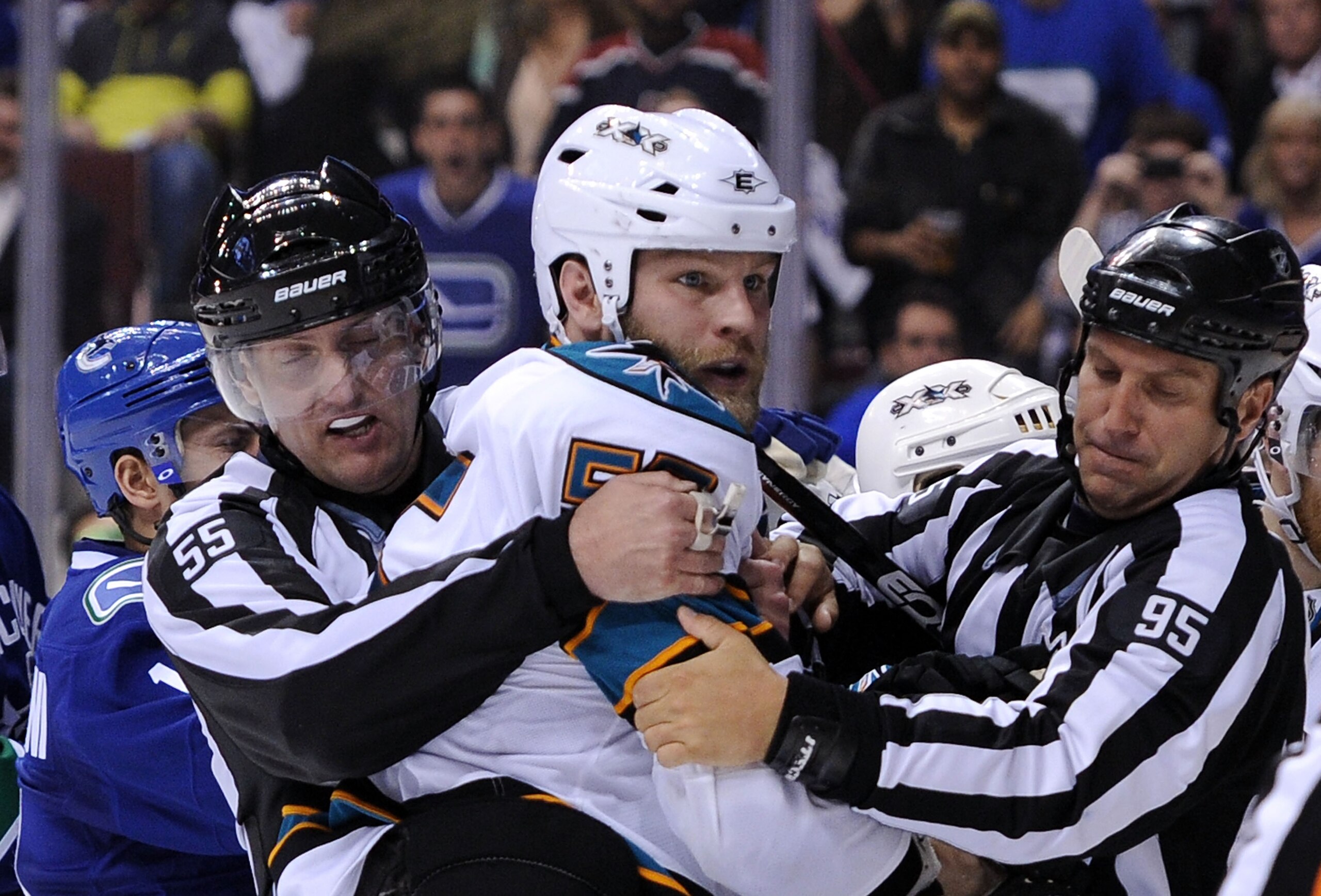 VANCOUVER, BC - MAY 18:  NHL Linesmen Shane Heyer #55 and Jonny Murray #95 hold back Ben Eager #55 of the San Jose Sharks as Eager gets called for an unsportsmanlike conduct penalty for standing over goaltender Roberto Luongo #1 of the Vancouver Canucks a