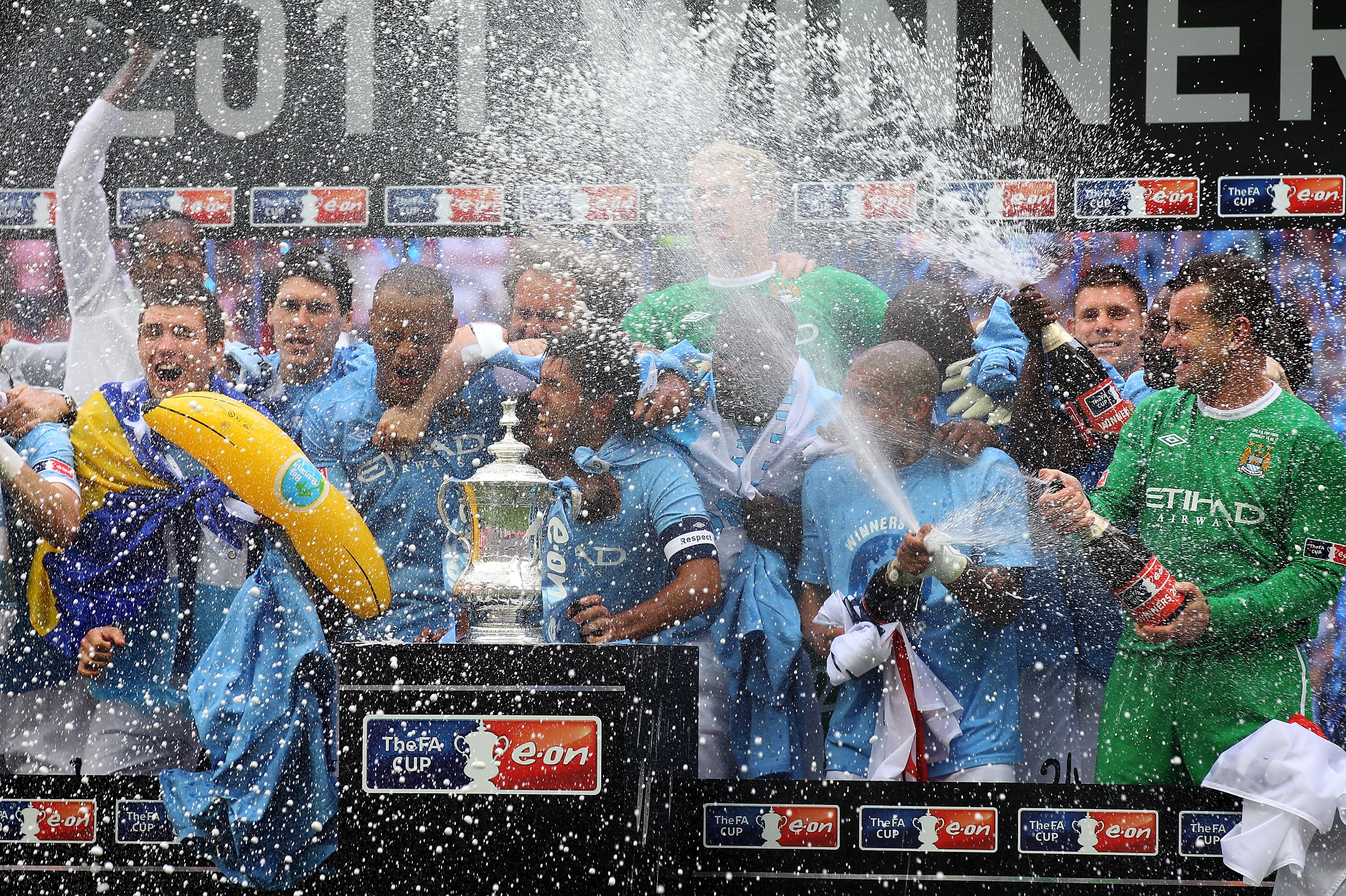 LONDON, ENGLAND - MAY 14:  Carlos Tevez of Manchester City and his team mates celebrate with champagne and the trophy after they won the FA Cup sponsored by E.ON Final match between Manchester City and Stoke City at Wembley Stadium on May 14, 2011 in Lond
