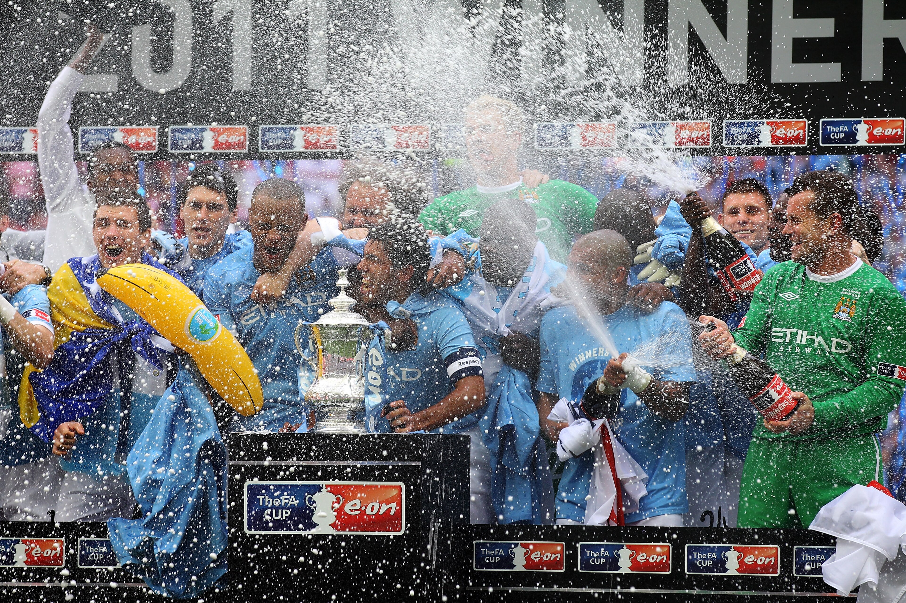 LONDON, ENGLAND - MAY 14:  Carlos Tevez of Manchester City and his team mates celebrate with champagne and the trophy after they won the FA Cup sponsored by E.ON Final match between Manchester City and Stoke City at Wembley Stadium on May 14, 2011 in Lond