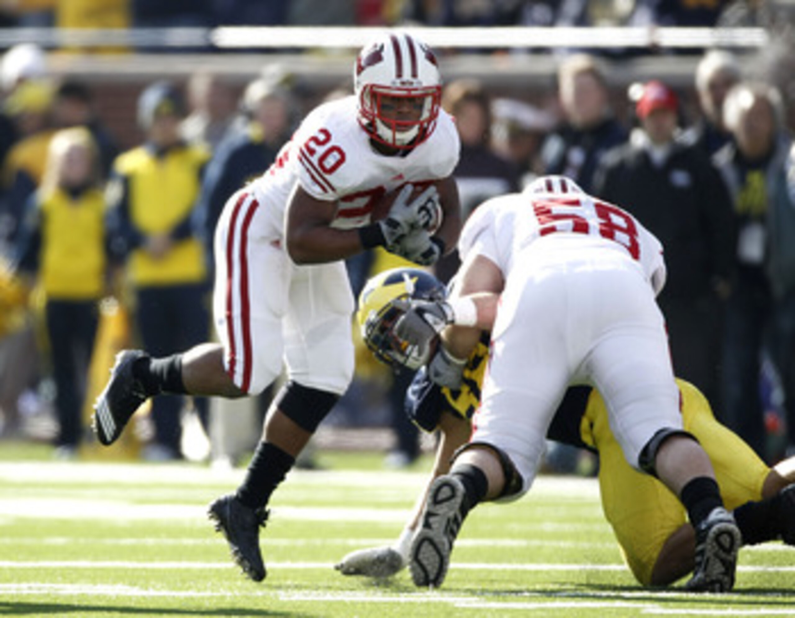 ANN ARBOR, MI - NOVEMBER 20: James White #20 of the Wisconsin Badgers jumps arond the block of teammate Ricky Wagner #58 while playing the Michigan Wolverines at Michigan Stadium on November 20, 2010 in Ann Arbor, Michigan.  (Photo by Gregory Shamus/Getty