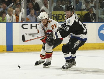 TAMPA, FL - JUNE 7:  Andrew Ference #21 of the Calgary Flames skates for the puck against Brad Richards #19 of the Tampa Bay Lightning in Game seven of the NHL Stanley Cup Finals on June 7, 2004 at the St. Pete Times Forum in Tampa, Florida. The Lightning