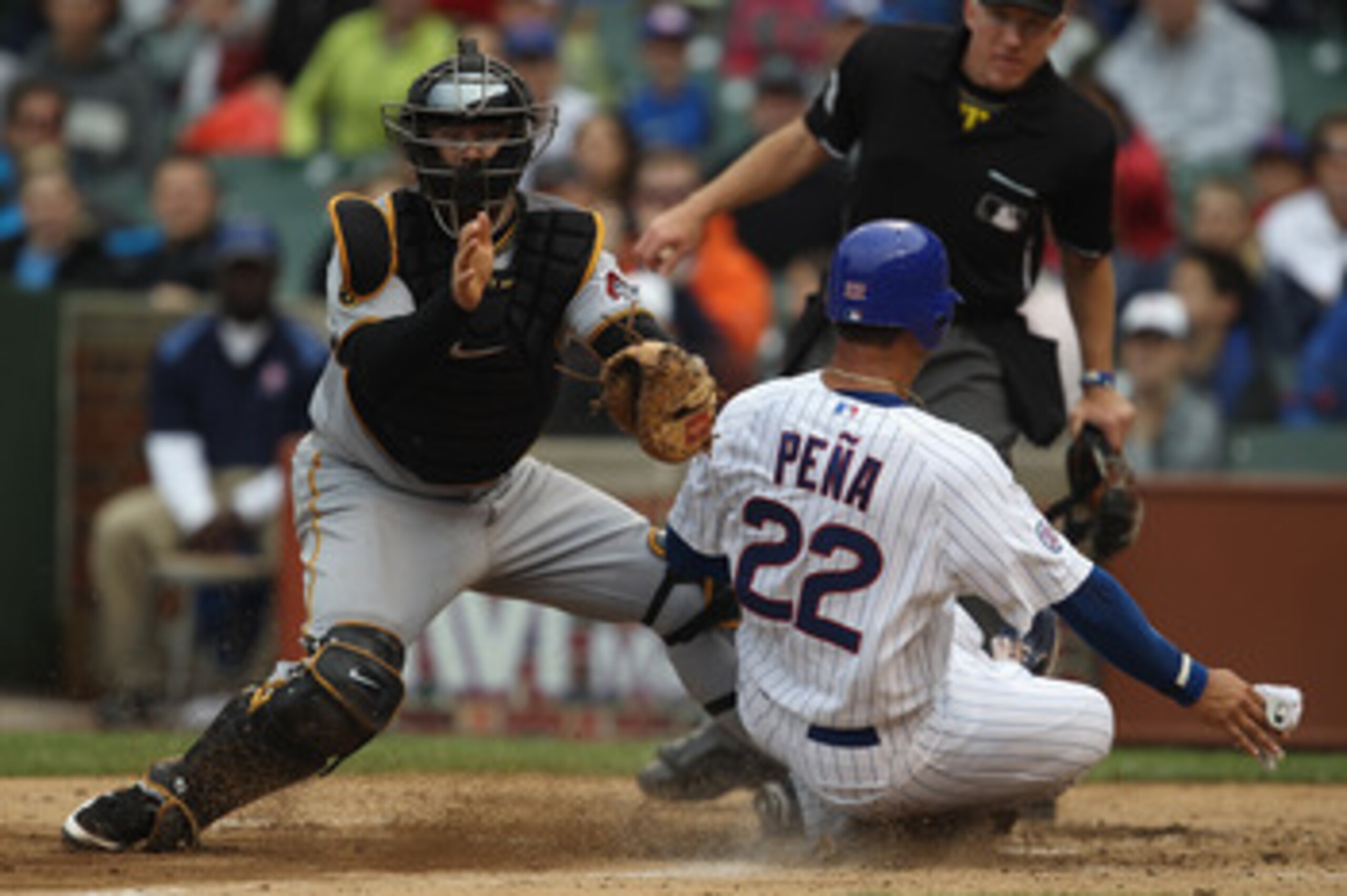 CHICAGO, IL - MAY 29: Carlos Pena #22 of the Chicago Cubs slides safely into home to score a run ahead of the tag by Ryan Doumit #41 of the Pittsburgh Pirates at Wrigley Field on May 29, 2011 in Chicago, Illinois. Doumit was injured on the play and left t