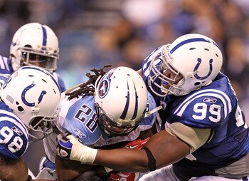 INDIANAPOLIS - JANUARY 02:  Chris Johnson #28 of the Tennessee Titans is tackled by Robert Mathis #98 and Antonio Johnson #99 of the Indianapolis Colts at Lucas Oil Stadium on January 2, 2011 in Indianapolis, Indiana.  the Colts won 23-20.  (Photo by Andy