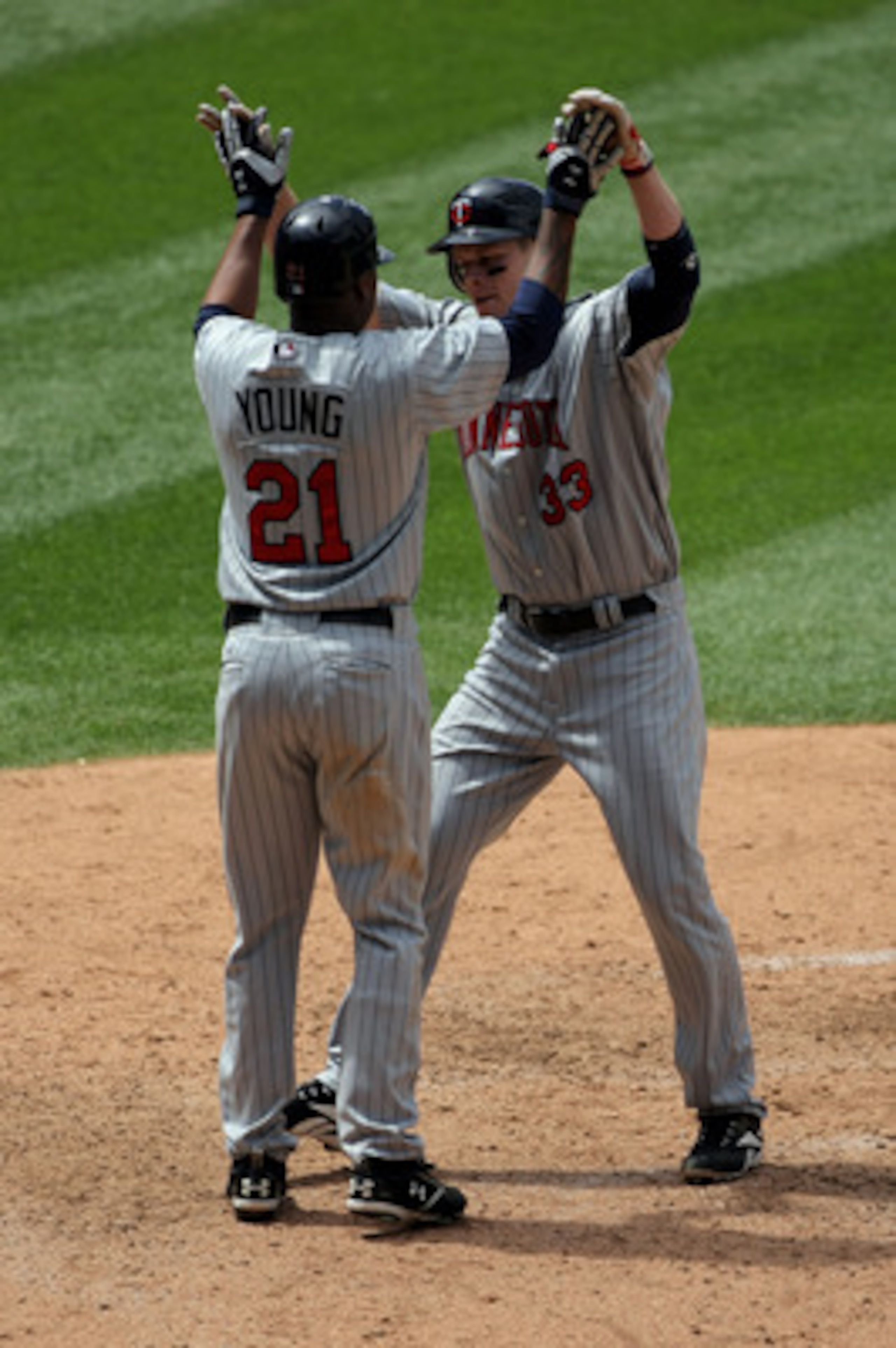 DENVER - MAY 18:  Delmon Young #21 welcomes home Justin Morneau #33 of the Minnesota Twins as they scored on Morneau's sixth inning home run against the Colorado Rockies during Interleague MLB action at Coors Field on May 18, 2008 in Denver, Colorado. The