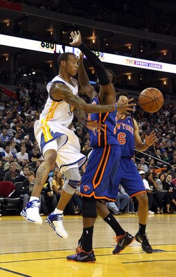 OAKLAND, CA - NOVEMBER 19:  Monta Ellis #8 of the Golden State Warriors passes around Ronny Turiaf #14 of the New York Knicks at Oracle Arena on November 19, 2010 in Oakland, California. NOTE TO USER: User expressly acknowledges and agrees that, by downlo