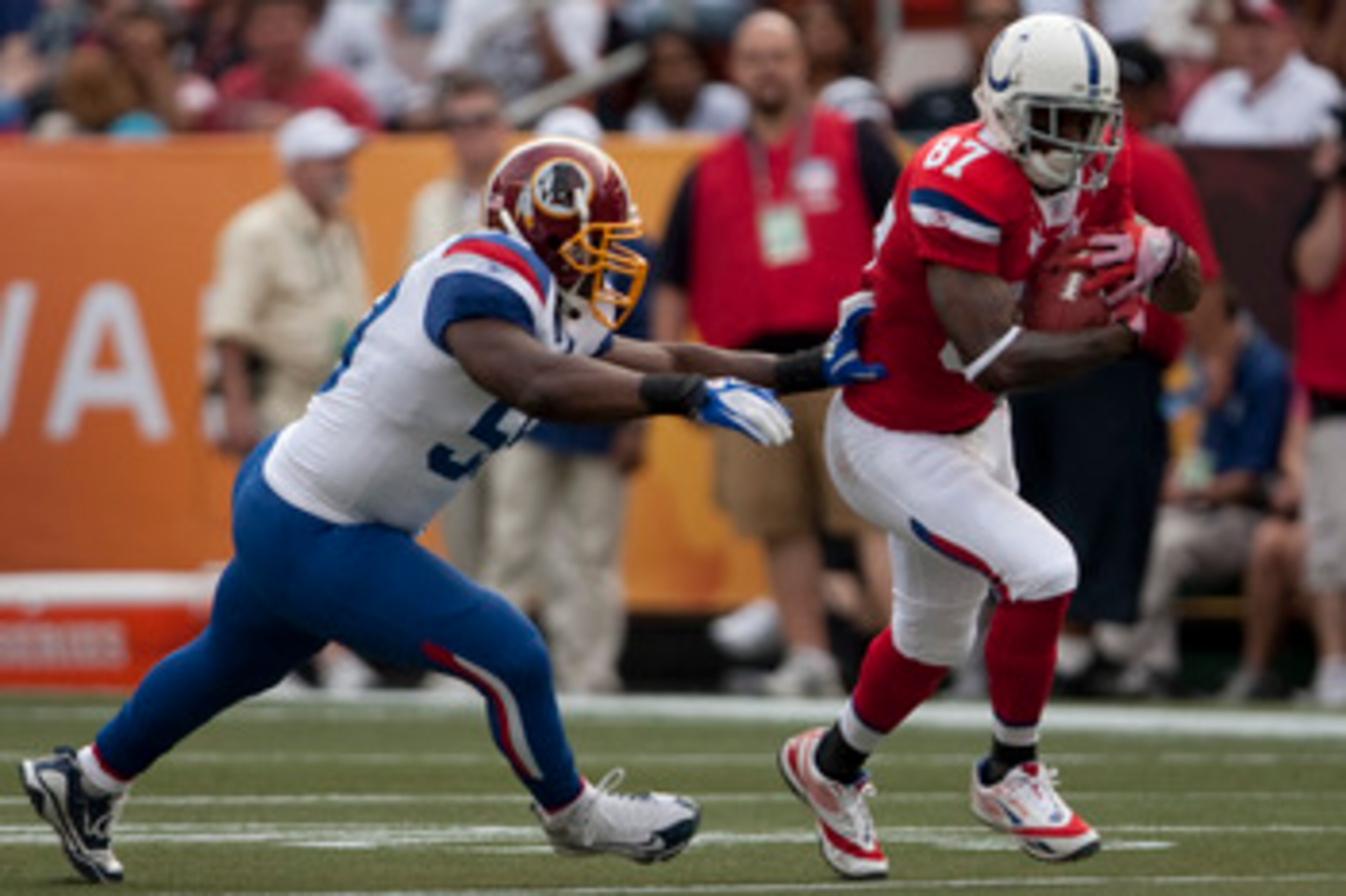 HONOLULU - JANUARY 30:  Reggie Wayne, #87 of the Indianapolis Colts, carries the ball while London Fletcher, #59 of the Washington Redskins, during the 2011 NFL Pro Bowl at Aloha Stadium on January 30, 2011 in Honolulu, Hawaii.  (Photo by Kent Nishimura/G