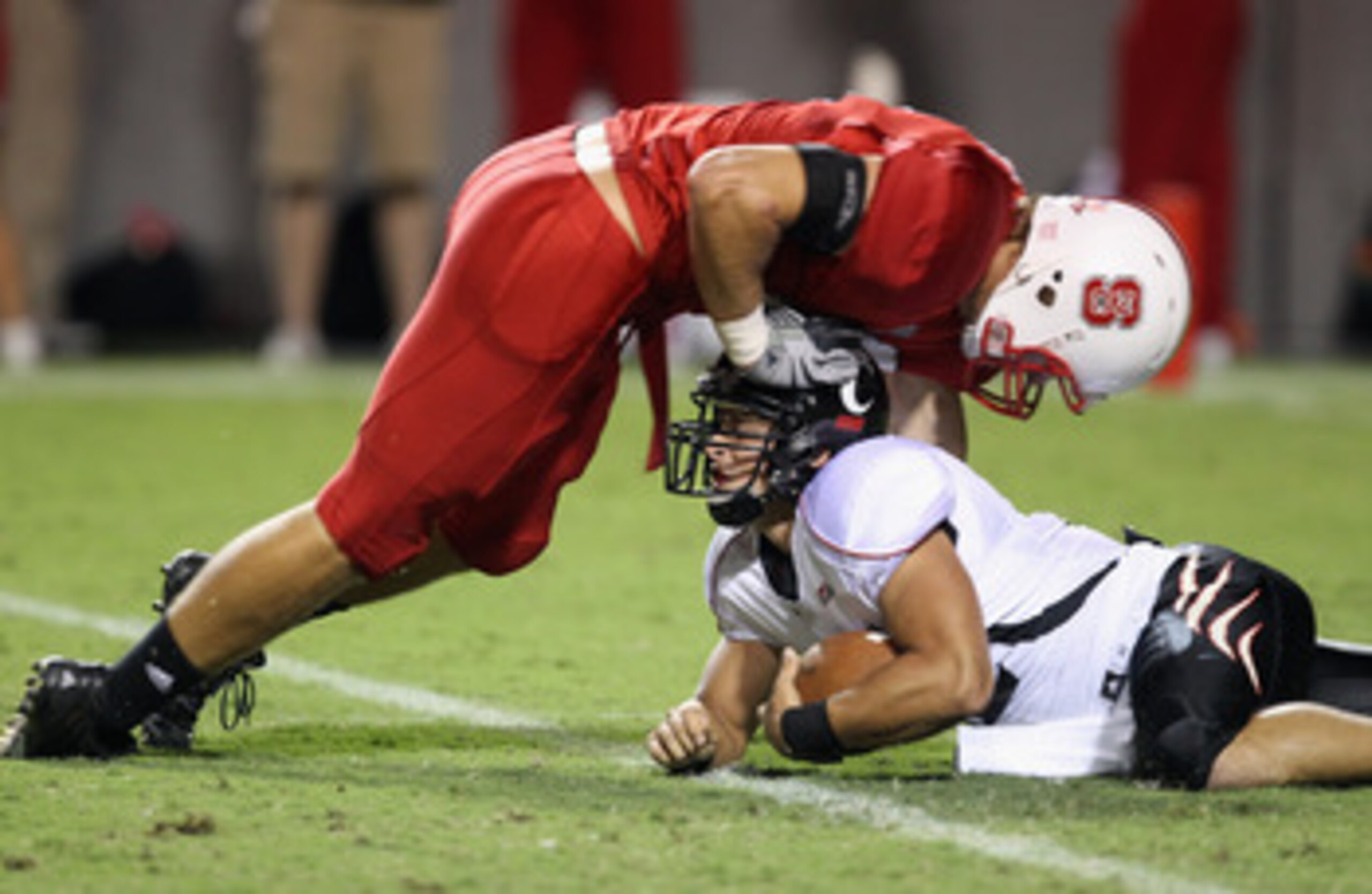 RALEIGH, NC - SEPTEMBER 16: Zack Collaros #12 of the Cincinnati Bearcats is tackled by Audie Cole #42 of the North Carolina State Wolfpack after recovering a fumble during their game at Carter-Finley Stadium on September 16, 2010 in Raleigh, North Caroli RALEIGH, NC - SEPTEMBER 16: Zack Collaros #12 of the Cincinnati Bearcats is tackled by Audie Cole #42 of the North Carolina State Wolfpack after recovering a fumble during their game at Carter-Finley Stadium on September 16, 2010 in Raleigh, North Caroli