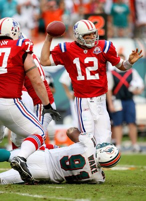 MIAMI - DECEMBER 06:  Quarterback Tom Brady #12 of the New England Patriots throws an interception late in the game while being hit by linebacker Cameron Wake #91 of the Miami Dolphins at Land Shark Stadium on December 6, 2009 in Miami, Florida. The Dolph