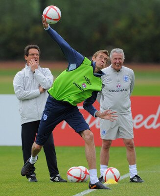 ST ALBANS, ENGLAND - MAY 31: Peter Crouch throws the ball as England manager Fabio Capello looks on during the England training session at London Colney on May 31, 2011 in St Albans, England.  (Photo by Michael Regan/Getty Images)