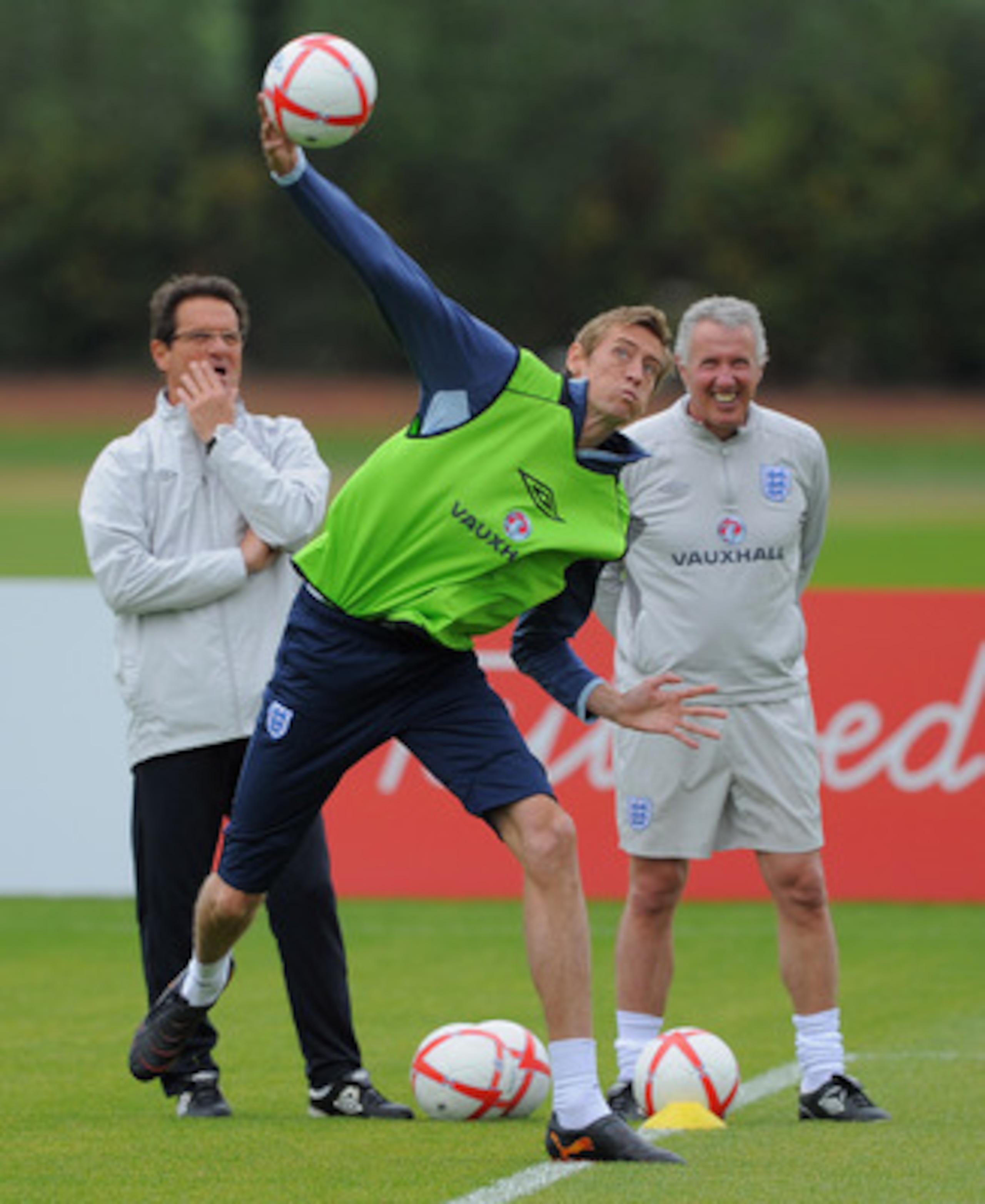 ST ALBANS, ENGLAND - MAY 31: Peter Crouch throws the ball as England manager Fabio Capello looks on during the England training session at London Colney on May 31, 2011 in St Albans, England.  (Photo by Michael Regan/Getty Images)