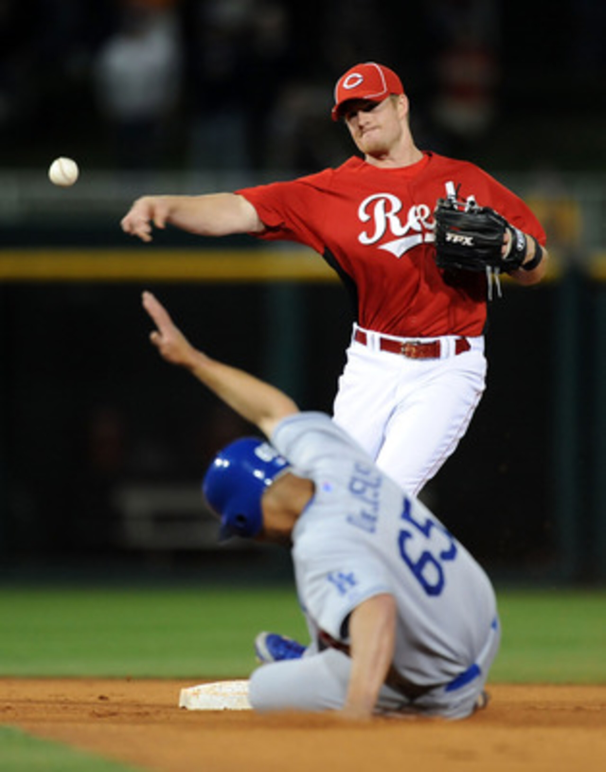 GOODYEAR, AZ - MARCH 03: Zack Cozart #60 of the Cincinnati Reds turns a double play as Ivan De Jesus #65 of the Los Angeles Dodgers slides into second base at Goodyear Ballpark on March 3, 2011 in Goodyear, Arizona.  (Photo by Norm Hall/Getty Images)