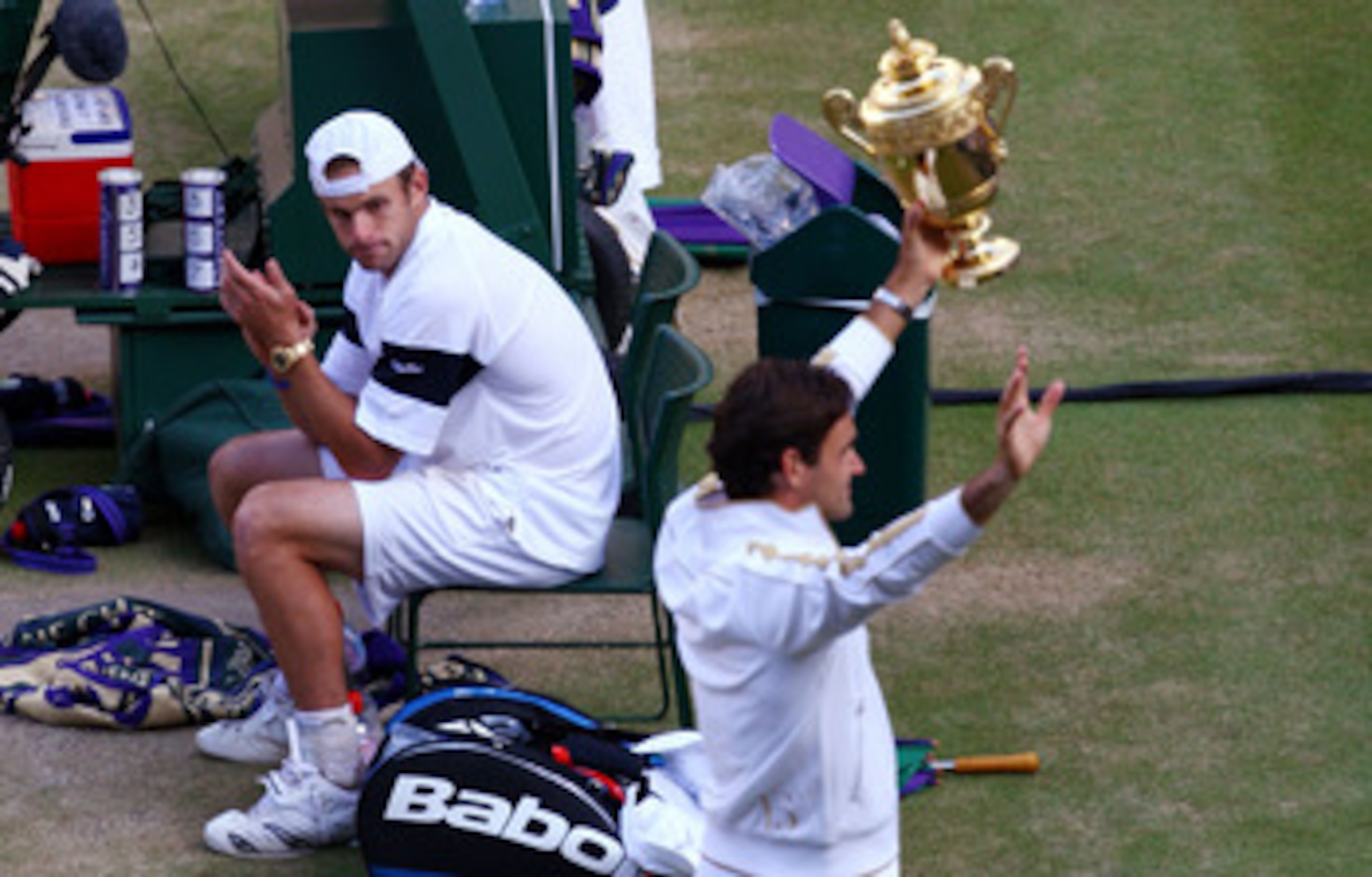 WIMBLEDON, ENGLAND - JULY 05:  Andy Roddick of USA looks despondent as Roger Federer of Switzerland celebrates with the trophy during the men's singles final match on Day Thirteen of the Wimbledon Lawn Tennis Championships at the All England Lawn Tennis a