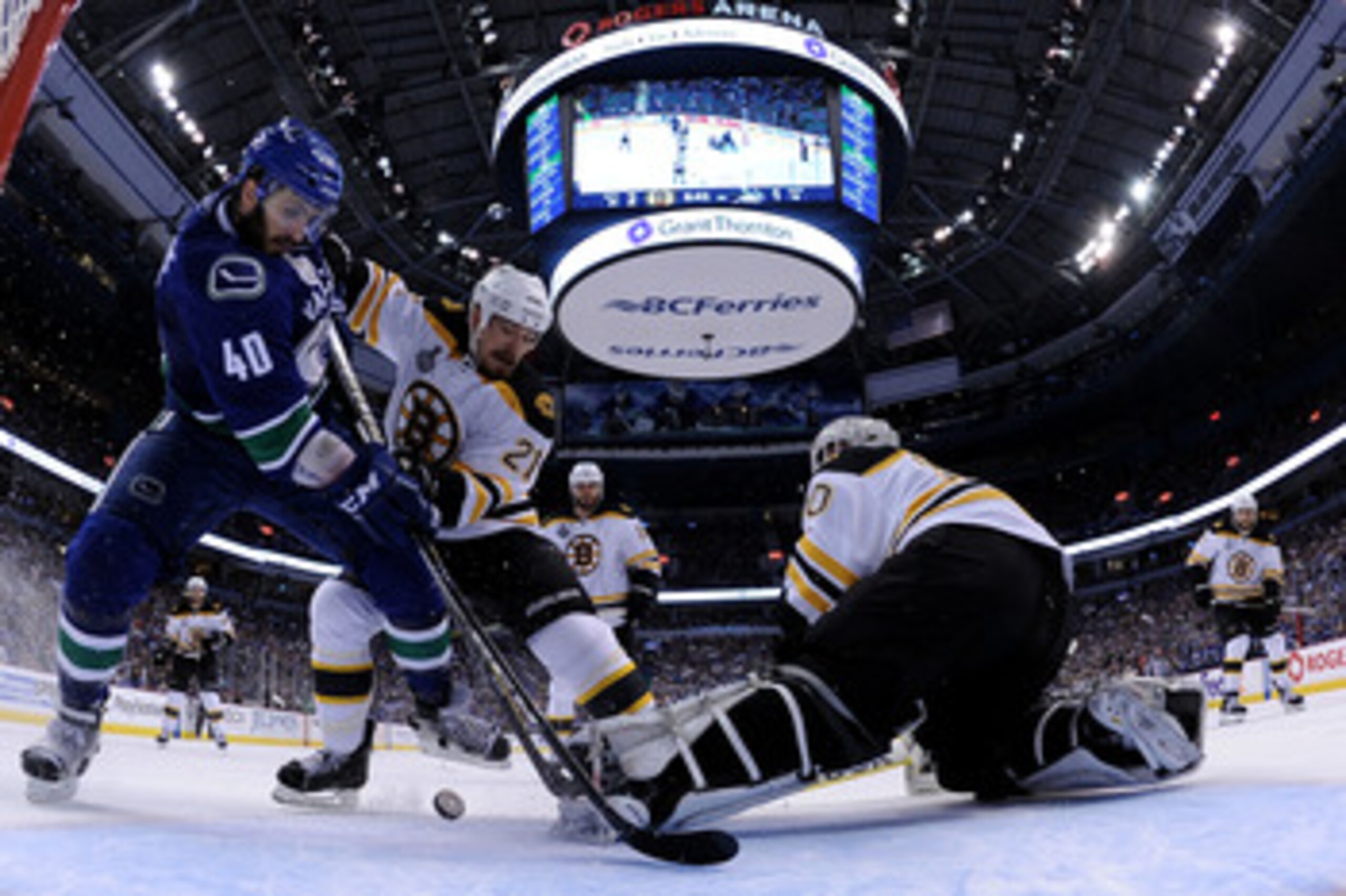 VANCOUVER, BC - JUNE 04:  Maxim Lapierre #40 of the Vancouver Canucks and Andrew Ference #21 of the Boston Bruins fight for the puck in front of Tim Thomas #30 of the Boston Bruins during Game Two of the 2011 NHL Stanley Cup Final at Rogers Arena on June 