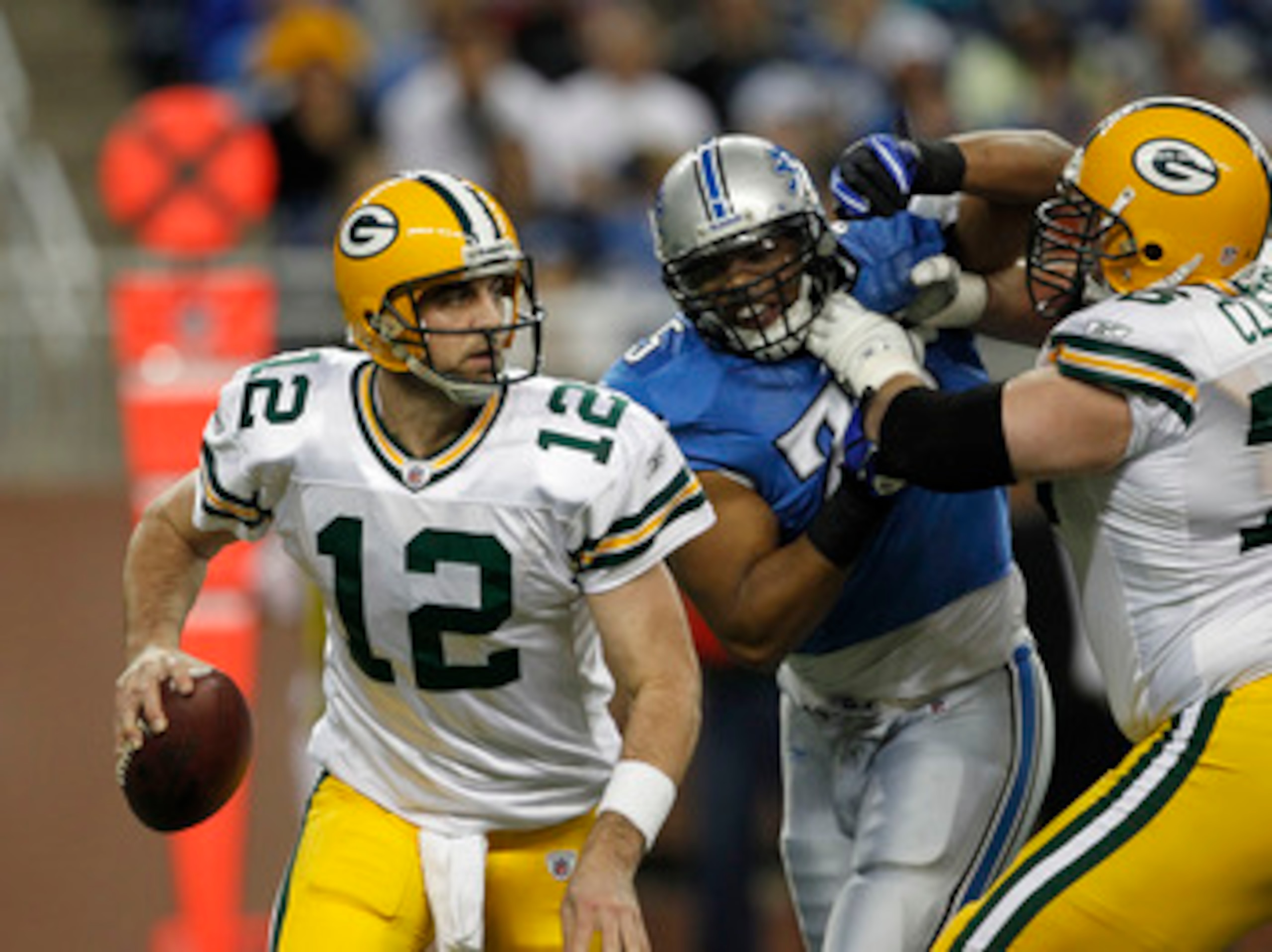 DETROIT - DECEMBER 12:  Aaron Rogers #12 of the Green Bay Packers rolls out to pass as Chad Clifton #76 of the Green Bay Packers blocks Turk McBride #75 of the Detroit lions during the second quarter of the game against the Detroit Lions at Ford Field on