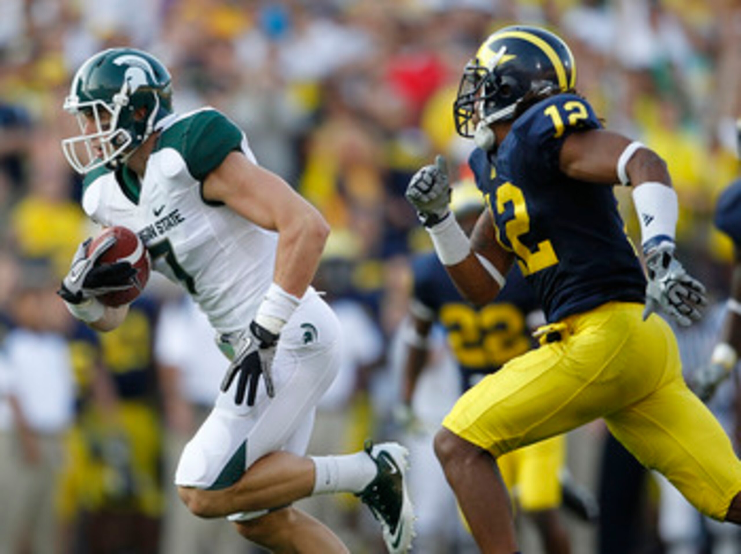 ANN ARBOR, MI - OCTOBER 09:  Steve Nichol #7 of the Michigan State Spartans runs past J. T. Floyd #12 of the Michigan Wolverines after catching a 42 yard pass compleation from Kirk Cousins #8 during the third quarter of the game against the Michigan Wolve