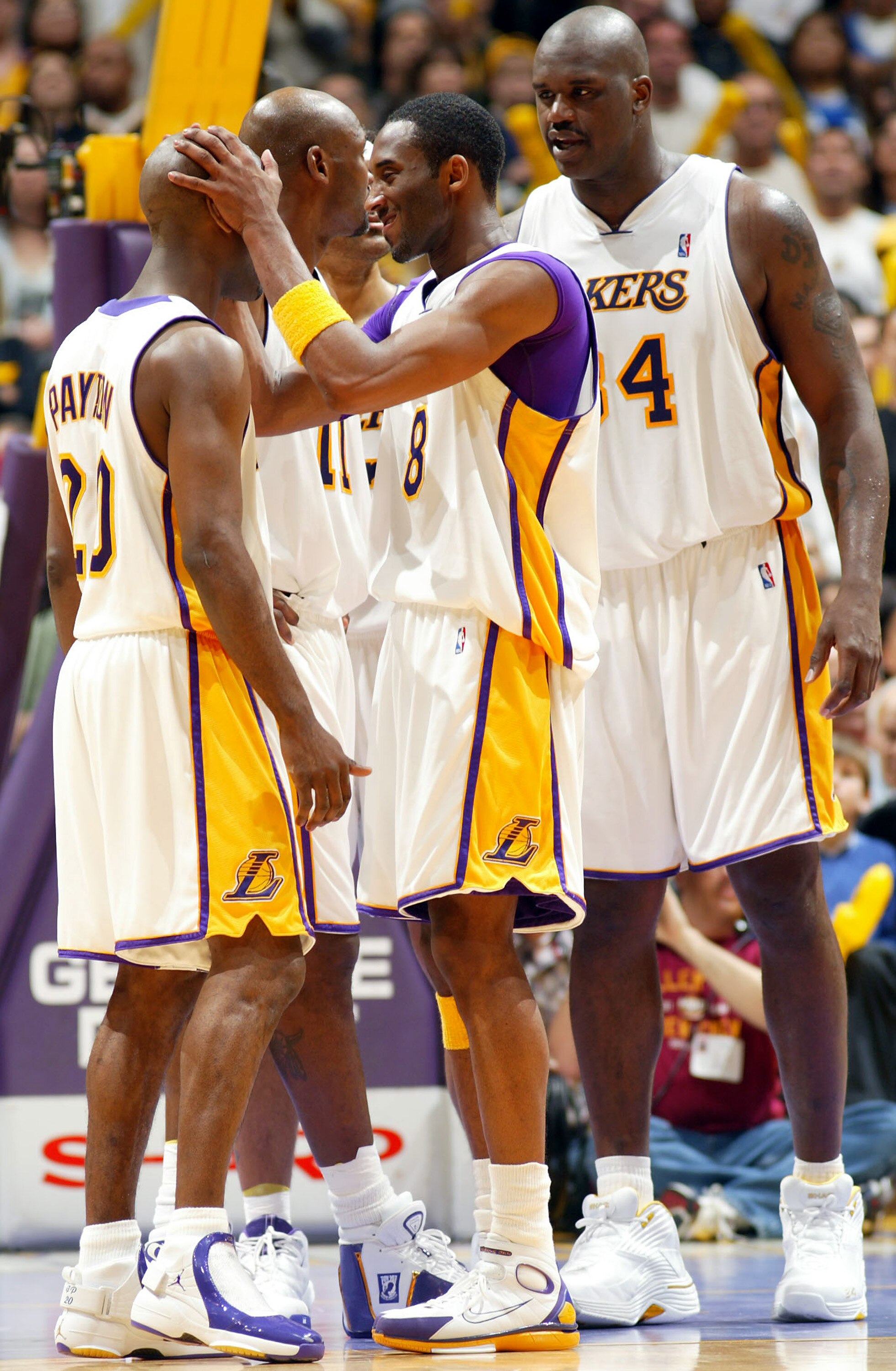 LOS ANGELES - MARCH 21:  Kobe Bryant #8 jokes with Gary Payton #20 of the Los Angeles Lakers as teammates Shaquille O'Neal #34 and Karl Malone #11 talk behind them during the game against the Milwaukee Bucks at Staples Center on March 21, 2004 in Los Ange