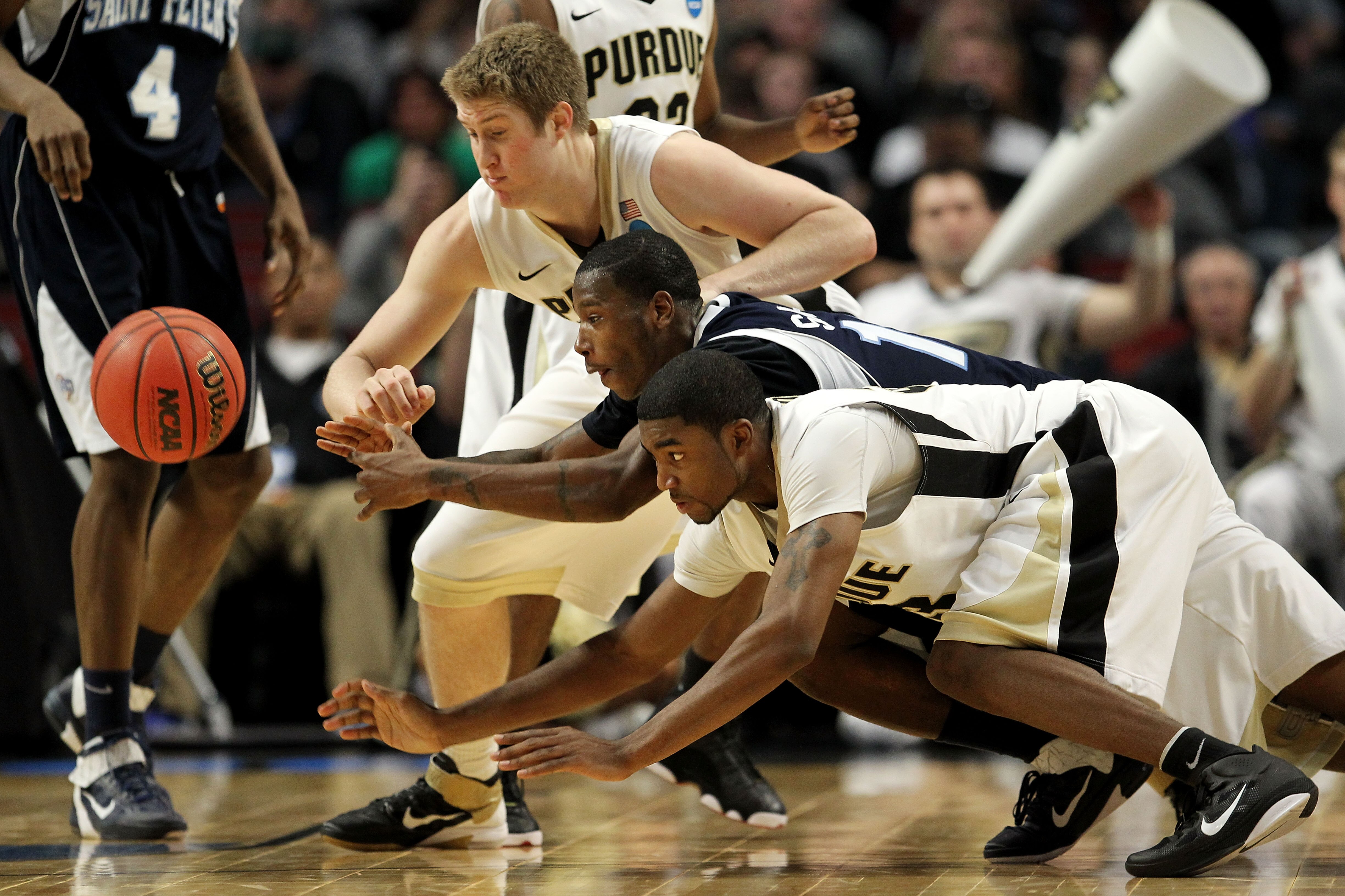 CHICAGO, IL - MARCH 18:  Steven Samuels #13 of the St. Peter's Peacocks scrambles for a ball against Travis Carroll #50 and E'Twaun Moore #33 of the Purdue Boilermakers in the second half during the second round of the 2011 NCAA men's basketball tournamen