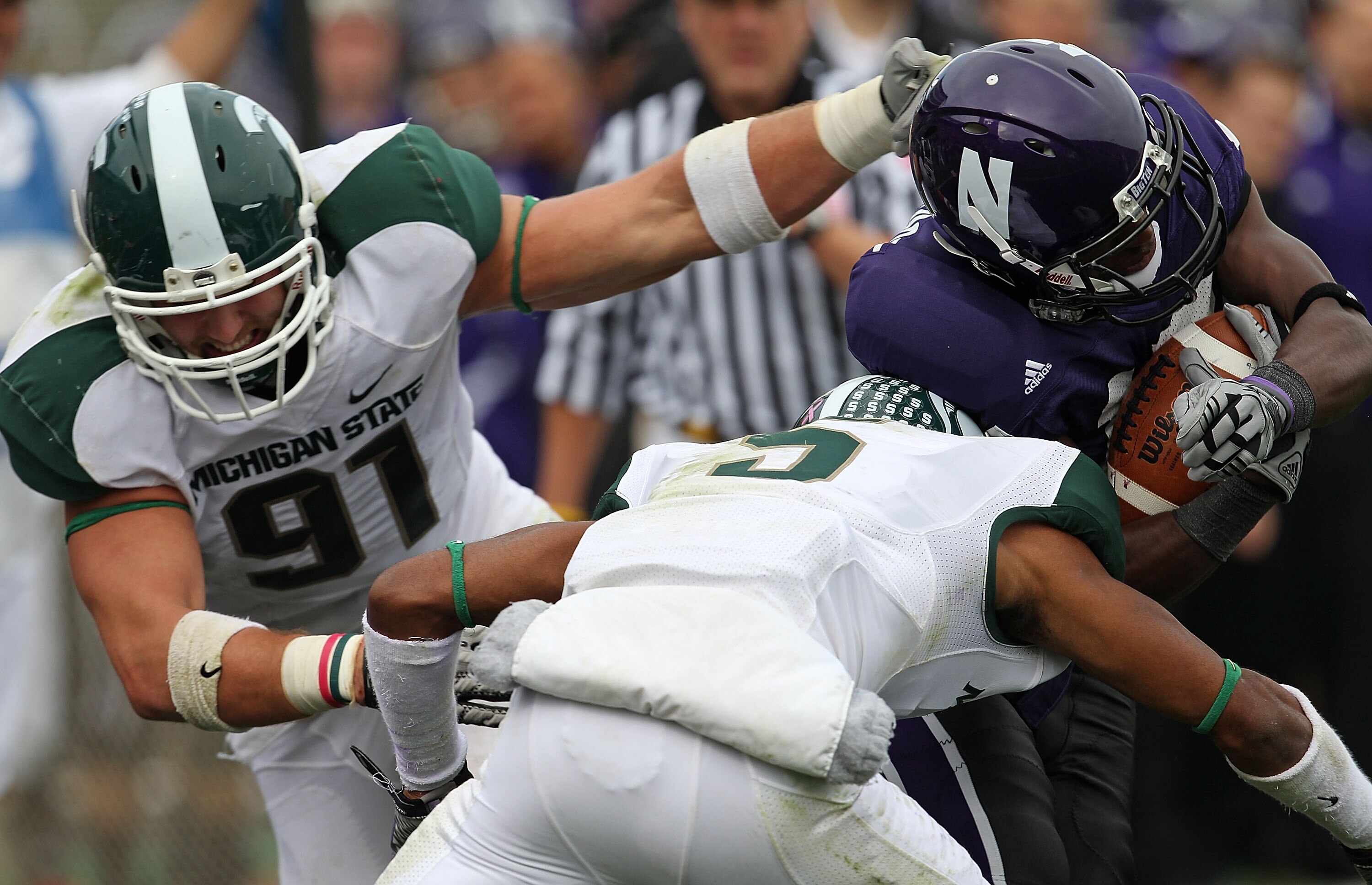 EVANSTON, IL - OCTOBER 23: Johnny Adams #5 and Tyler Hoover #91 of the Michigan State Spartans bring down Rashad Lawrence #17 of the Northwestern Wildcats at Ryan Field on October 23, 2010 in Evanston, Illinois. Michigan State defeated Northwestern 35-27.