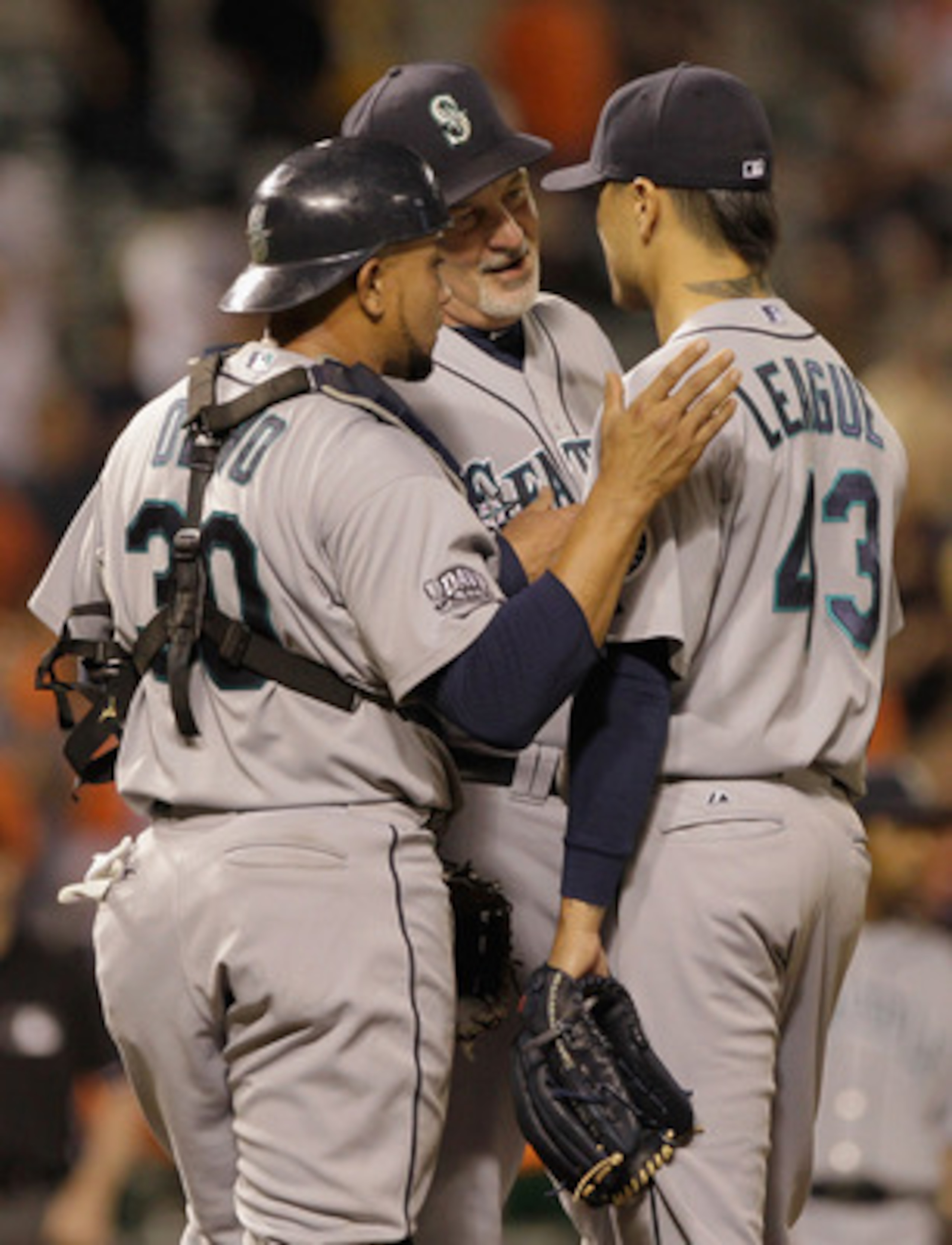 BALTIMORE, MD - MAY 12: Pitching coach Carl Willis #48 (C) talks with reliever Brandon League #43 and catcher Miguel Olivo #30 of the Seattle Mariners on the mound during the twelfth inning against the Baltimore Orioles at Oriole Park at Camden Yards on M