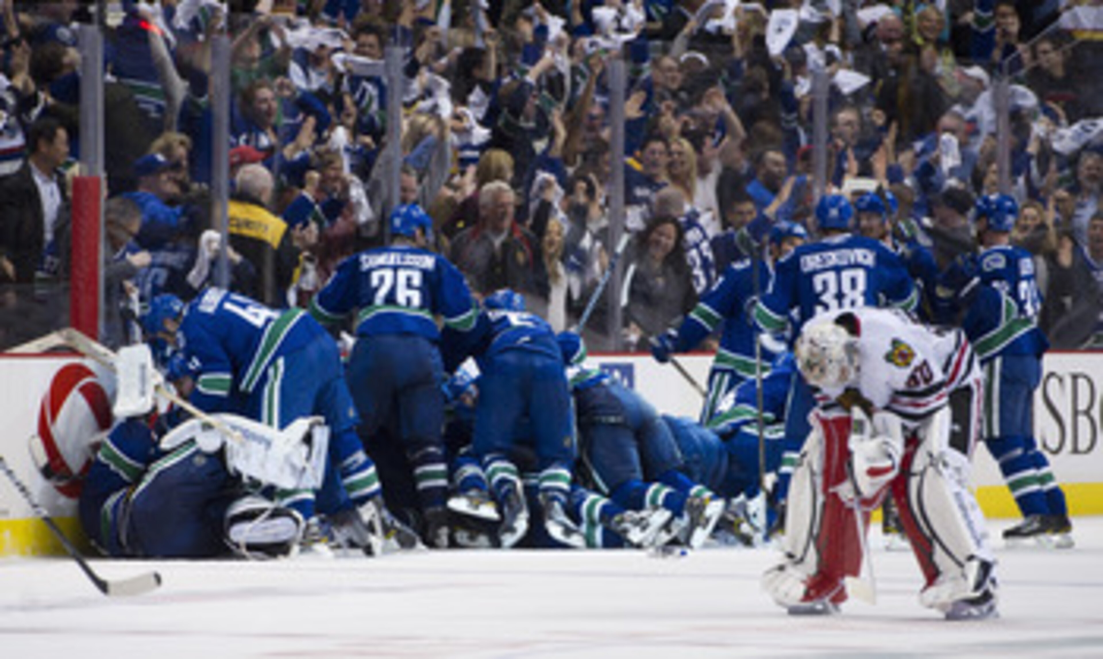 VANCOUVER, CANADA - APRIL 26: The Vancouver Canucks celebrate after defeating the Chicago Blackhawks 2-1 in overtime as goalie Corey Crawford #50 Chicago Blackhawks skates back to his after Game Seven of the Western Conference Quarterfinals during the 201