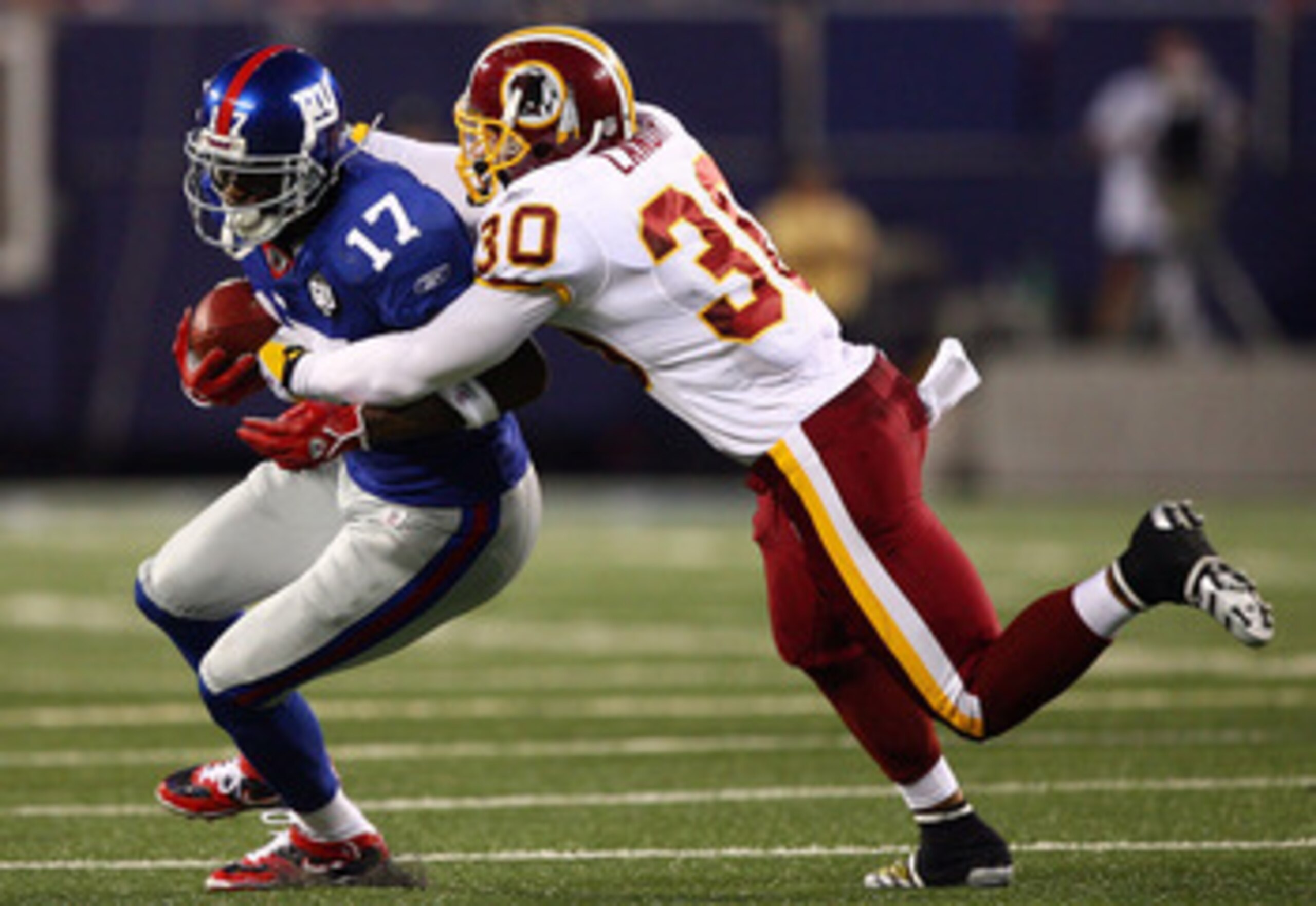 EAST RUTHERFORD, NJ - SEPTEMBER 04:  Plaxico Burress #17 of the New York Giants tries to break the tackle of LaRon Landry #30 of the Washington Redskins at Giants Stadium on September 4, 2008 in East Rutherford, New Jersey  (Photo by Al Bello/Getty Images