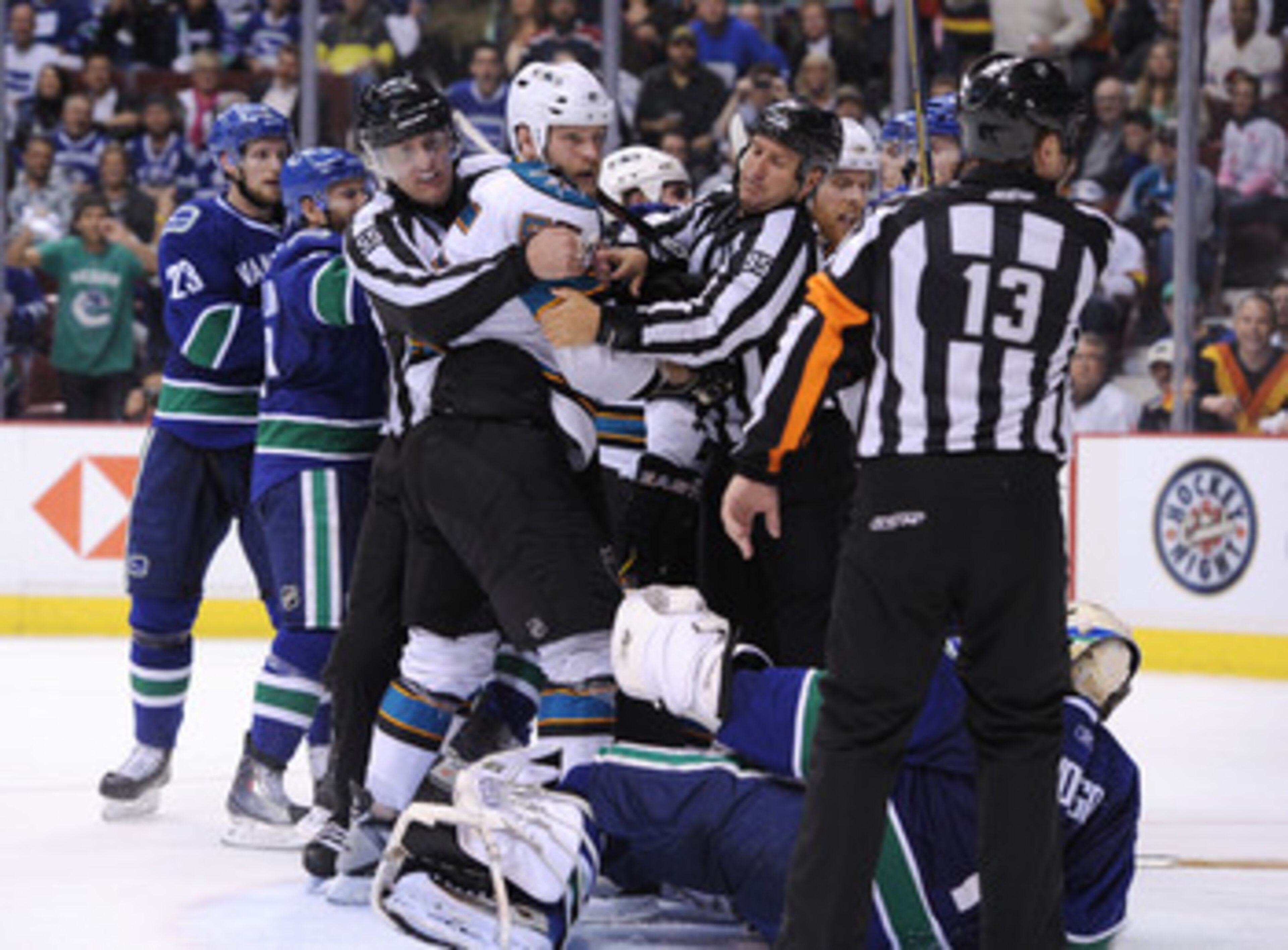 VANCOUVER, BC - MAY 18:  NHL Linesmen Shane Heyer #55 and Jonny Murray #95 hold back Ben Eager #55 of the San Jose Sharks as Eager gets called for an unsportsmanlike conduct penalty for standing over goaltender Roberto Luongo #1 of the Vancouver Canucks a