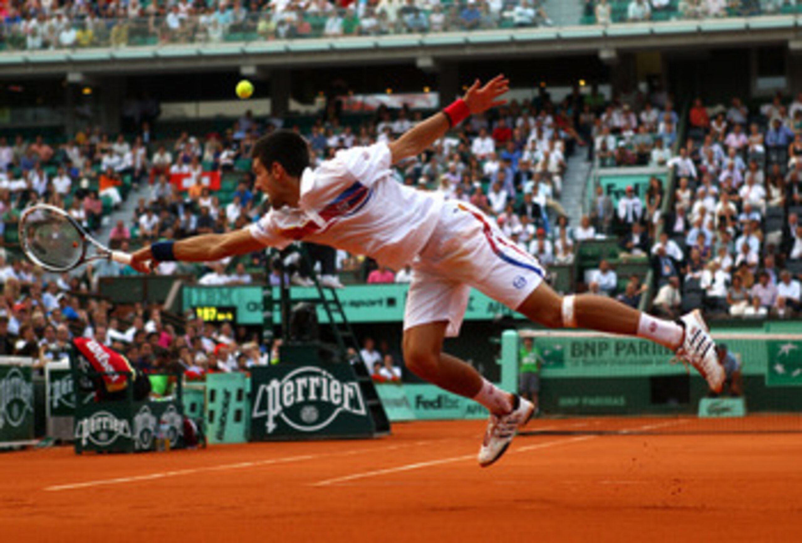 PARIS, FRANCE - JUNE 03:  Novak Djokovic of Serbia stretches to hit a backhand during the men's singles semi final match between Roger Federer of Switzerland and Novak Djokovic of Serbia on day thirteen of the French Open at Roland Garros on June 3, 2011