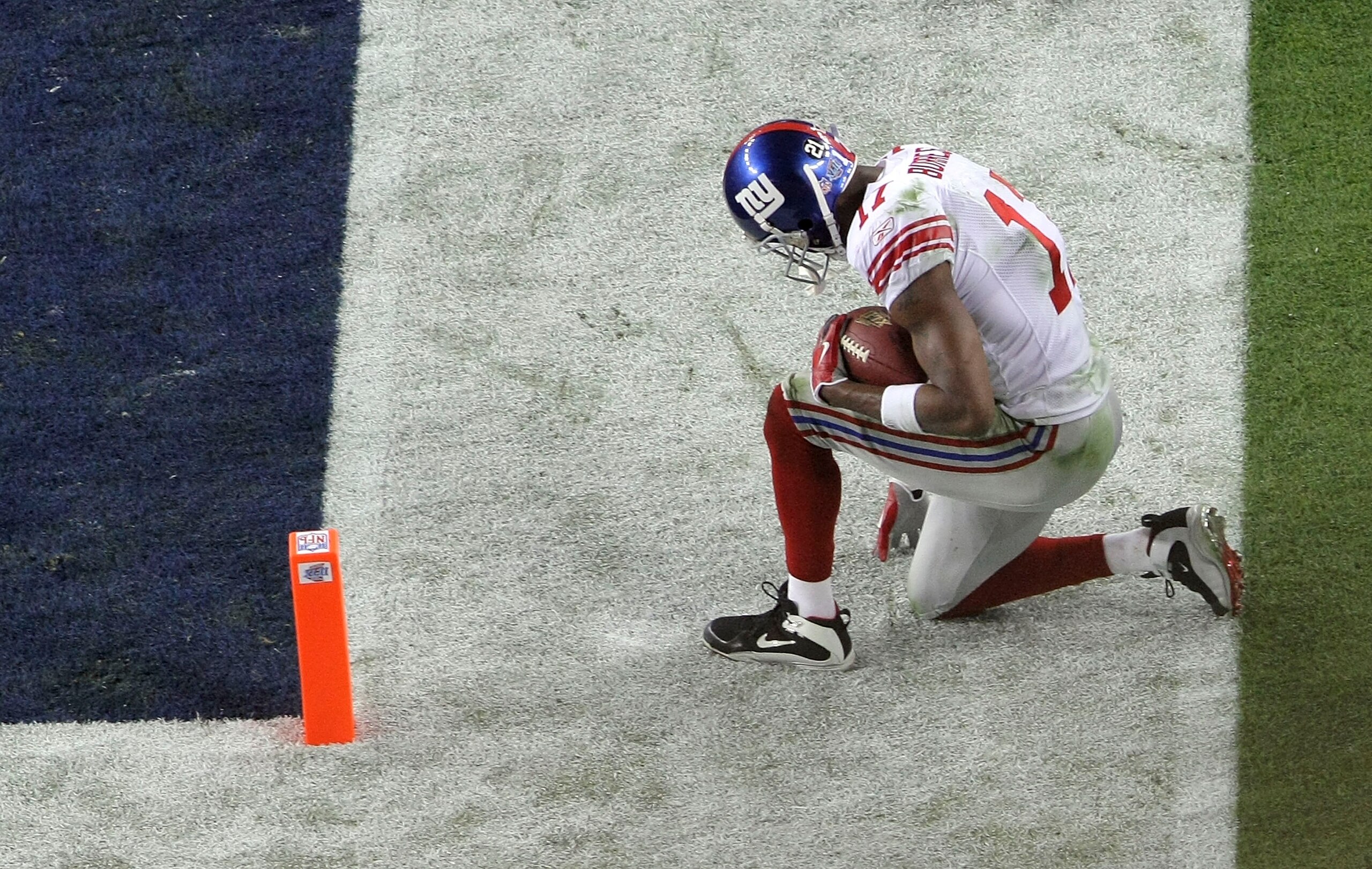 GLENDALE, AZ - FEBRUARY 03:  Plaxico Burress #17 of the New York Giants kneels just outside the endzone after he scored on a 13-yard touchdown reception in the fourth quarter against the New England Patriots during Super Bowl XLII on February 3, 2008 at t