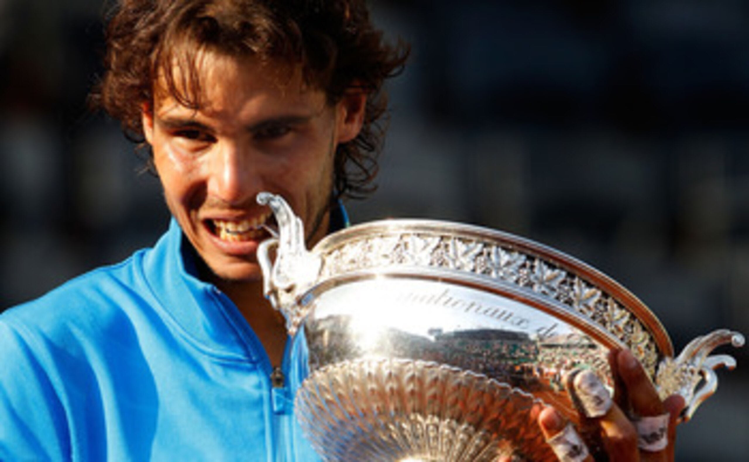 PARIS, FRANCE - JUNE 05:  Champion Rafael Nadal of Spain bites the trophy following his record equalling sixth victory during the men's singles final match between Rafael Nadal of Spain and Roger Federer of Switzerland on day fifteen of the French Open at