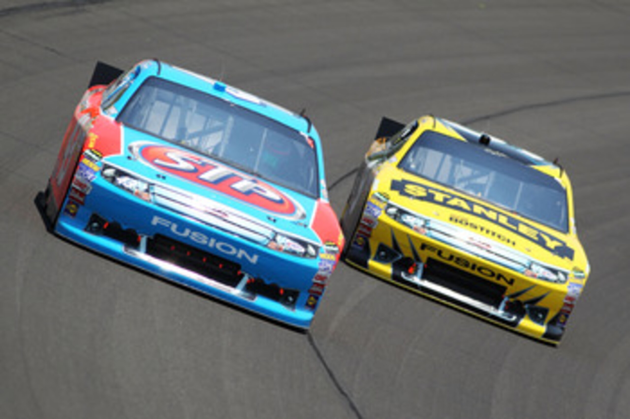 KANSAS CITY, KS - JUNE 05:  A.J. Allmendinger, driver of the #43 STP Ford, races Marcos Ambrose, driver of the #9 Stanley Ford, during the NASCAR Sprint Cup Series STP 400 at Kansas Speedway on June 5, 2011 in Kansas City, Kansas.  (Photo by Jamie Squire/