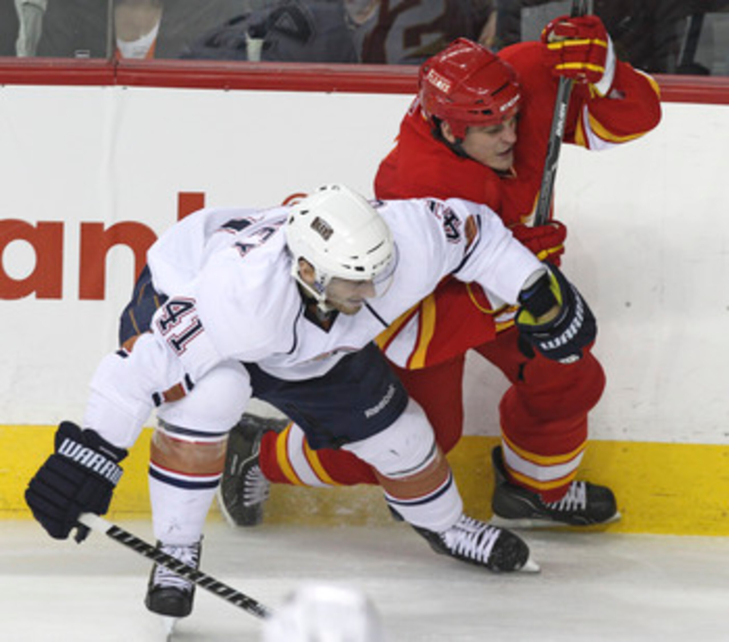 CALGARY, CANADA - APRIL 6: Lance Bouma #57 of the Calgary Flames is pinned to the boards by Taylor Chorney #41 of the Edmonton Oilers in third period NHL action on April 6, 2011 at the Scotiabank Saddledome in Calgary, Alberta, Canada. (Photo by Mike Ride