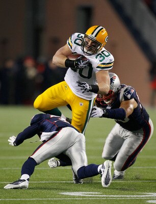 FOXBORO, MA - DECEMBER 19:  Running back John Kuhn #30 of the Green Bay Packers is tackled by linebacker Tully Banta-Cain #95 and cornerback Devin McCourty #32 of the New England Patriots during the first quarter of the game at Gillette Stadium on Decembe