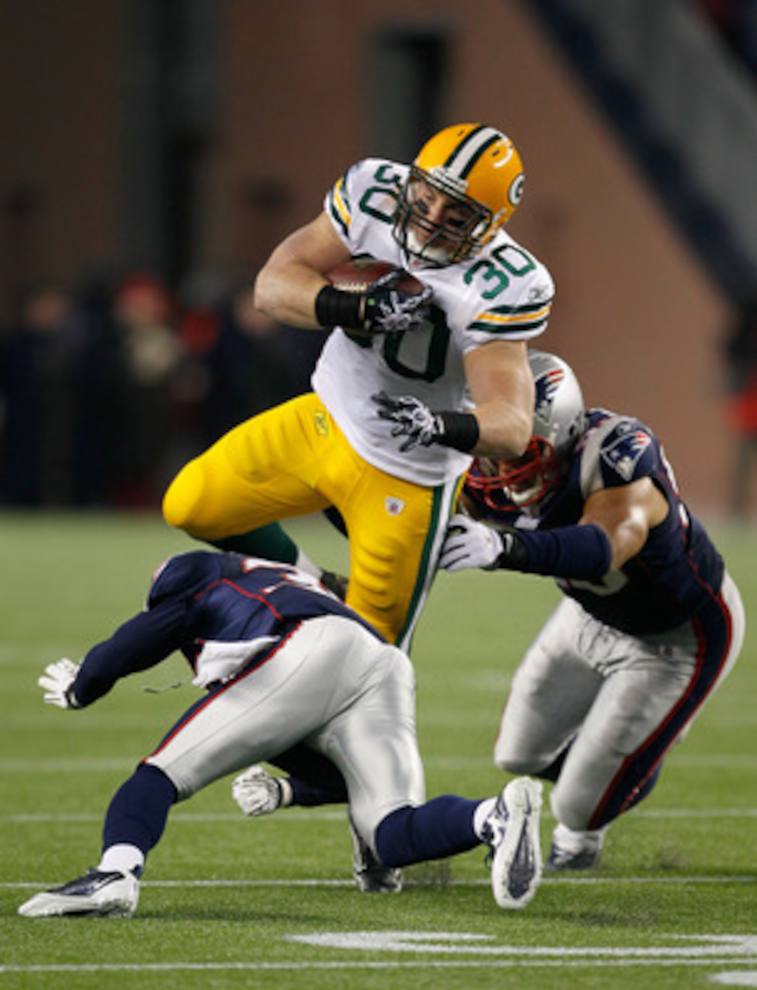 FOXBORO, MA - DECEMBER 19:  Running back John Kuhn #30 of the Green Bay Packers is tackled by linebacker Tully Banta-Cain #95 and cornerback Devin McCourty #32 of the New England Patriots during the first quarter of the game at Gillette Stadium on Decembe