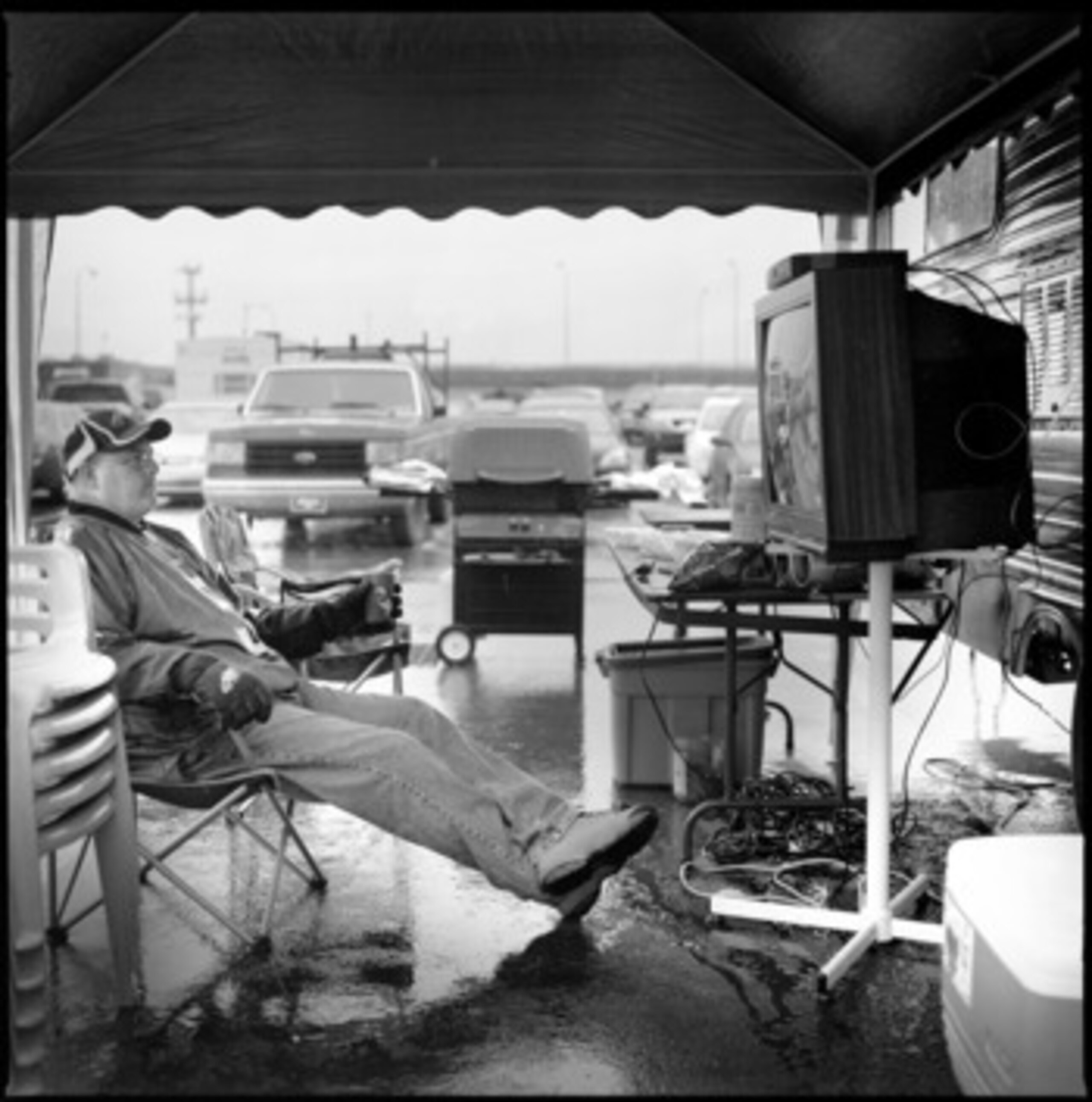 PHILADELPHIA - NOVEMBER 18:  Tailgater Joe Hammond sits in the rain watching the Miami Dolphins play against the Philadelphia Eagles on his make shift tv in the stadium carpark after giving away his ticket to a friends son, during the NFL game between the