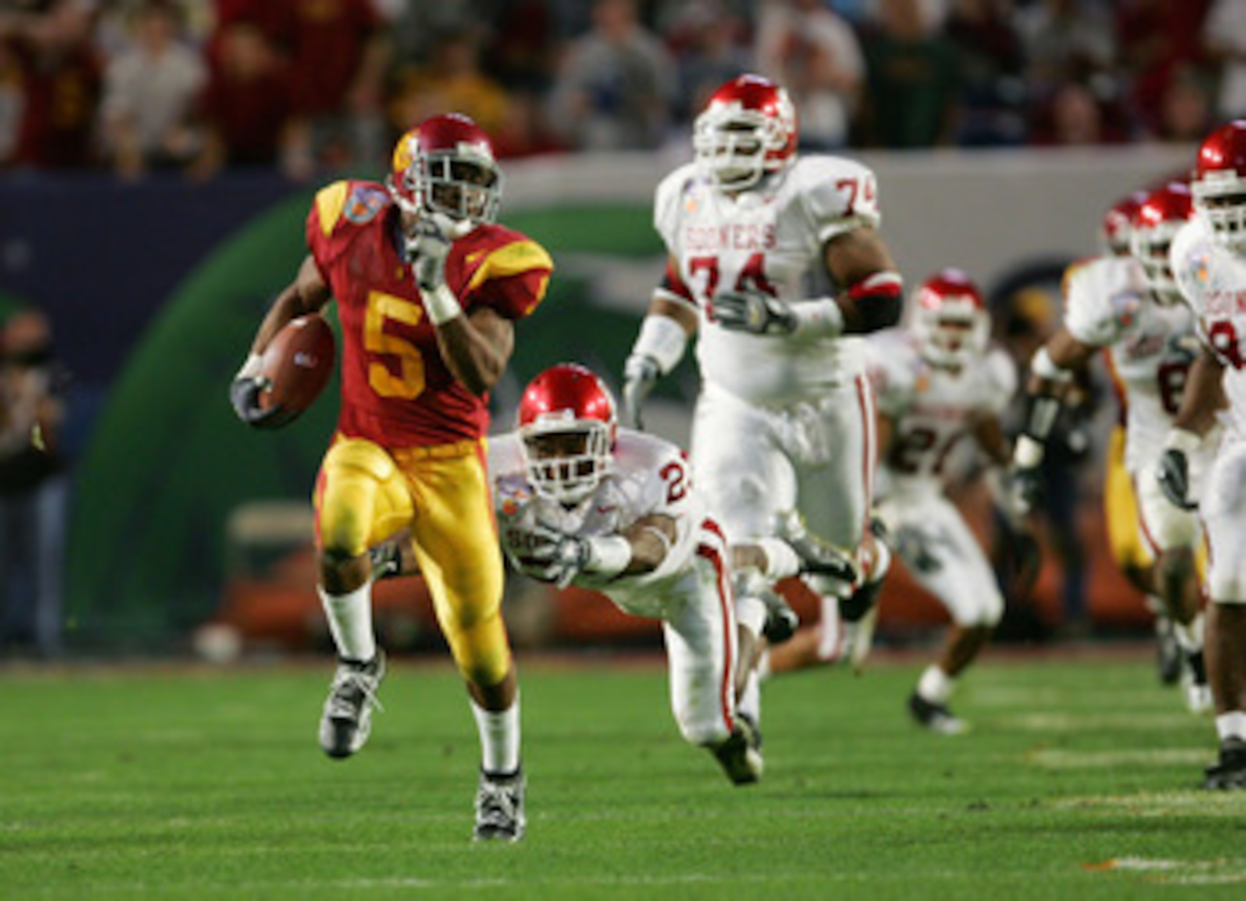 MIAMI - JANUARY 4: Running back Reggie Bush #5 of the USC Trojans runs upfield against safety Brodney Pool #23 and the Oklahoma Sooners in the 2005 FedEx Orange Bowl National Championship on January 4, 2005 at Pro Player Stadium in Miami, Florida. USC d MIAMI - JANUARY 4: Running back Reggie Bush #5 of the USC Trojans runs upfield against safety Brodney Pool #23 and the Oklahoma Sooners in the 2005 FedEx Orange Bowl National Championship on January 4, 2005 at Pro Player Stadium in Miami, Florida. USC d