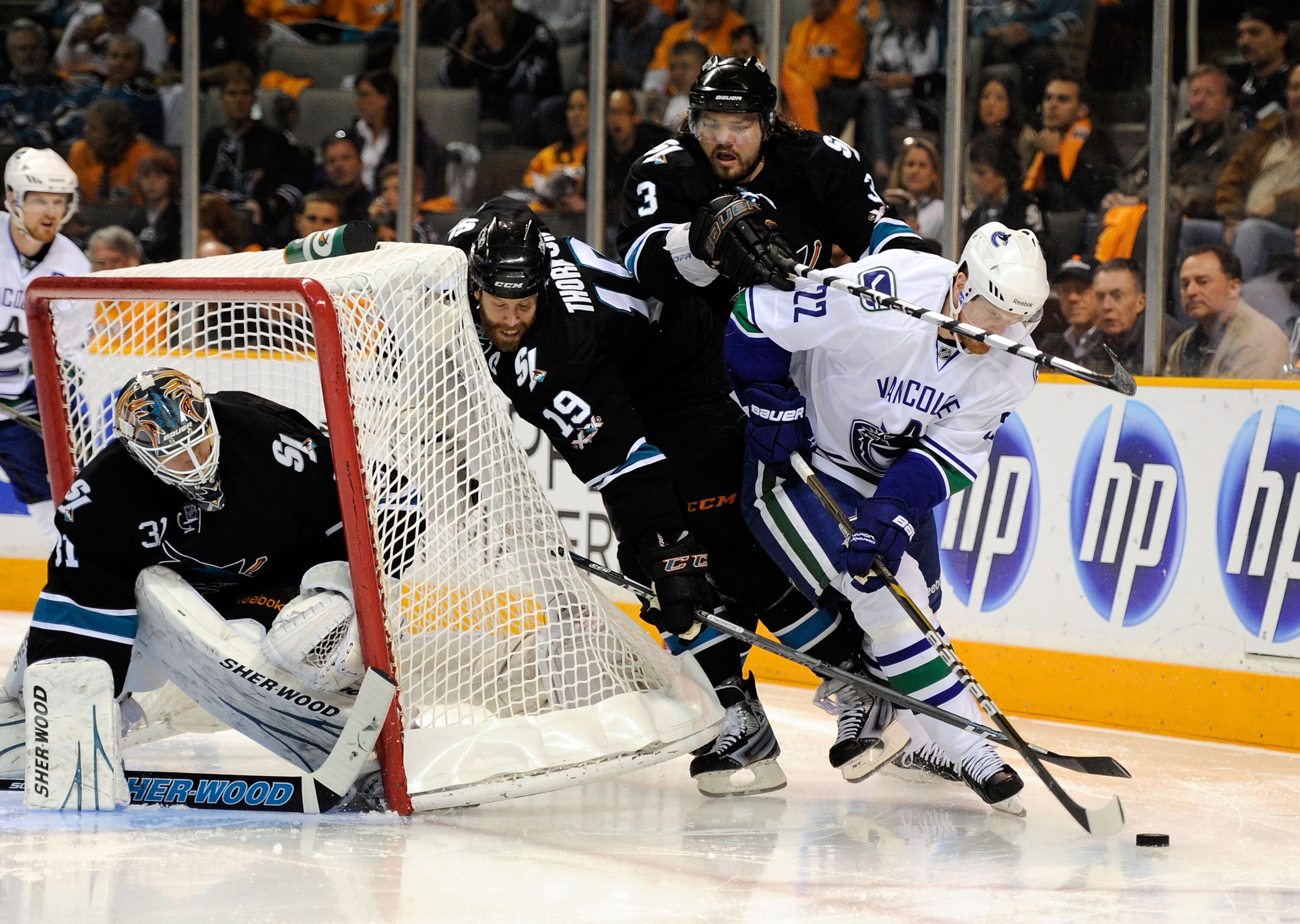SAN JOSE, CA - MAY 20:  Daniel Sedin #22 of the Vancouver Canucks brings the puck from behind the net around Joe Thornton #19 and Douglas Murray #3 of the San Jose Sharks in the second period in Game Three of the Western Conference Finals during the 2011