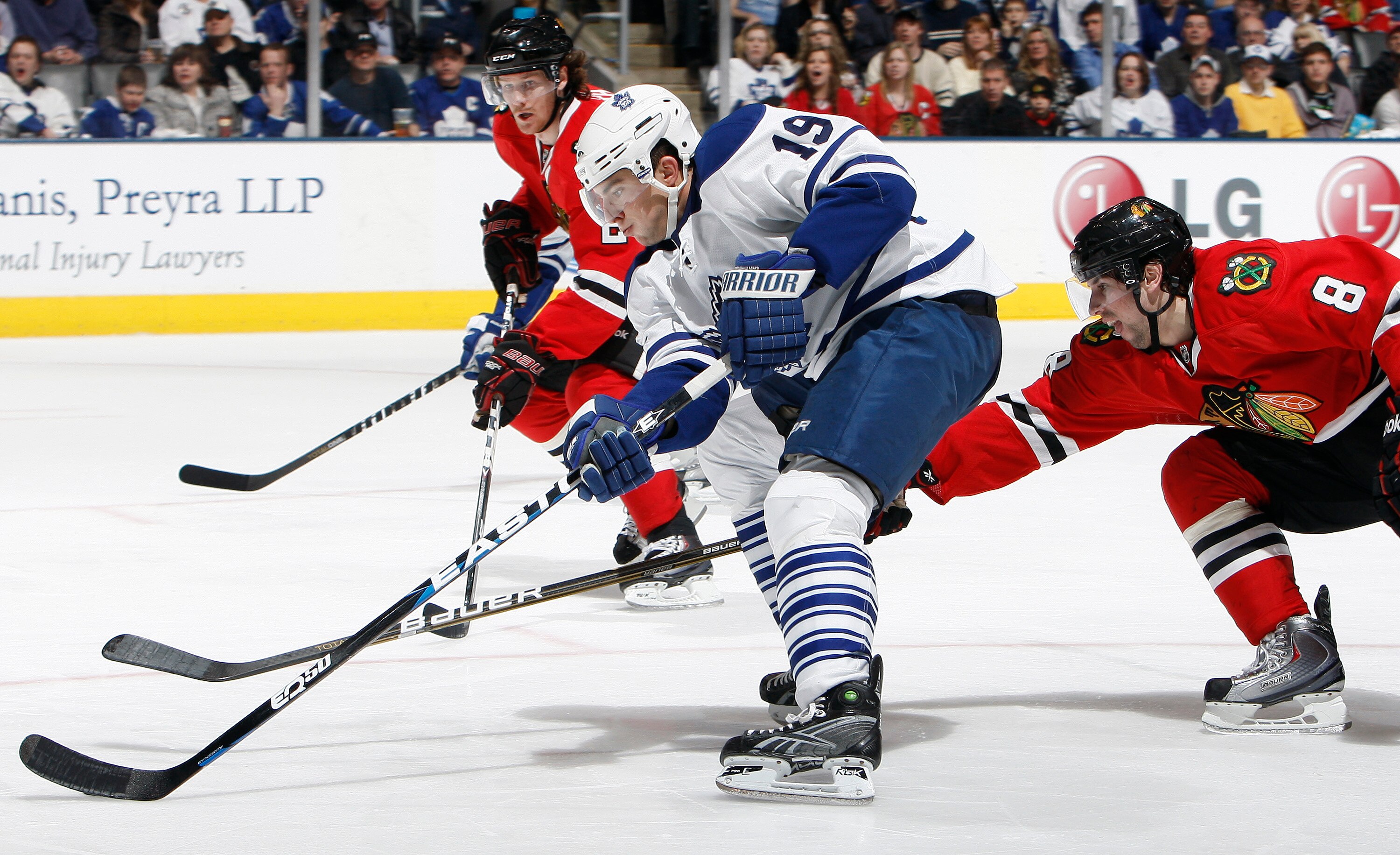 TORONTO, CANADA - MARCH 5: Joffrey Lupul #19 of the Toronto Maple Leafs drives the net on Nick Leddy #8 and Duncan Keith #2 of the Chicago Blackhawks during game action at the Air Canada Centre March 5, 2011 in Toronto, Ontario, Canada. (Photo by Abelimag