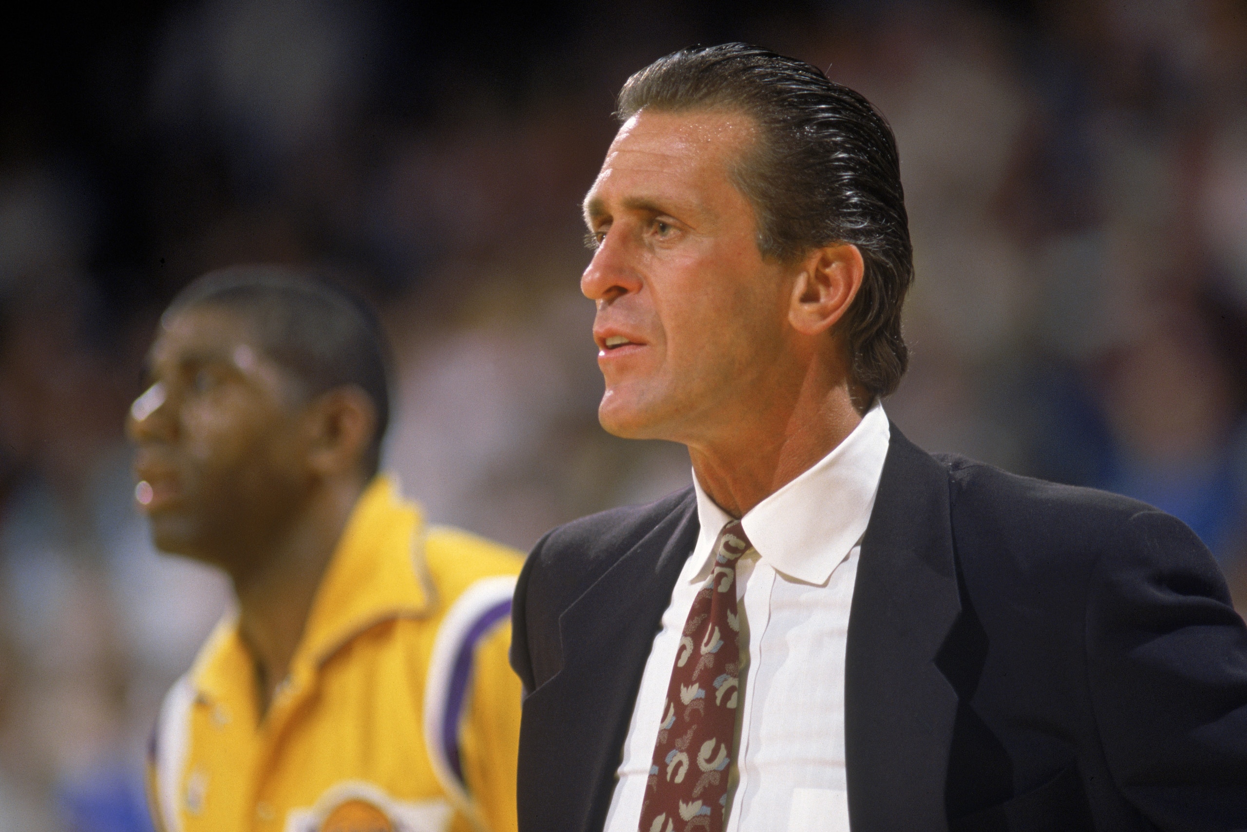 LOS ANGELES - 1988:  Head coach Pat Riley of the Los Angeles Lakers stands on the sideline in front of Magic Johnson #32 during an NBA game at the Great Western Forum in Los Angeles, California in 1988. (Photo by: Mike Powell/Getty Images)