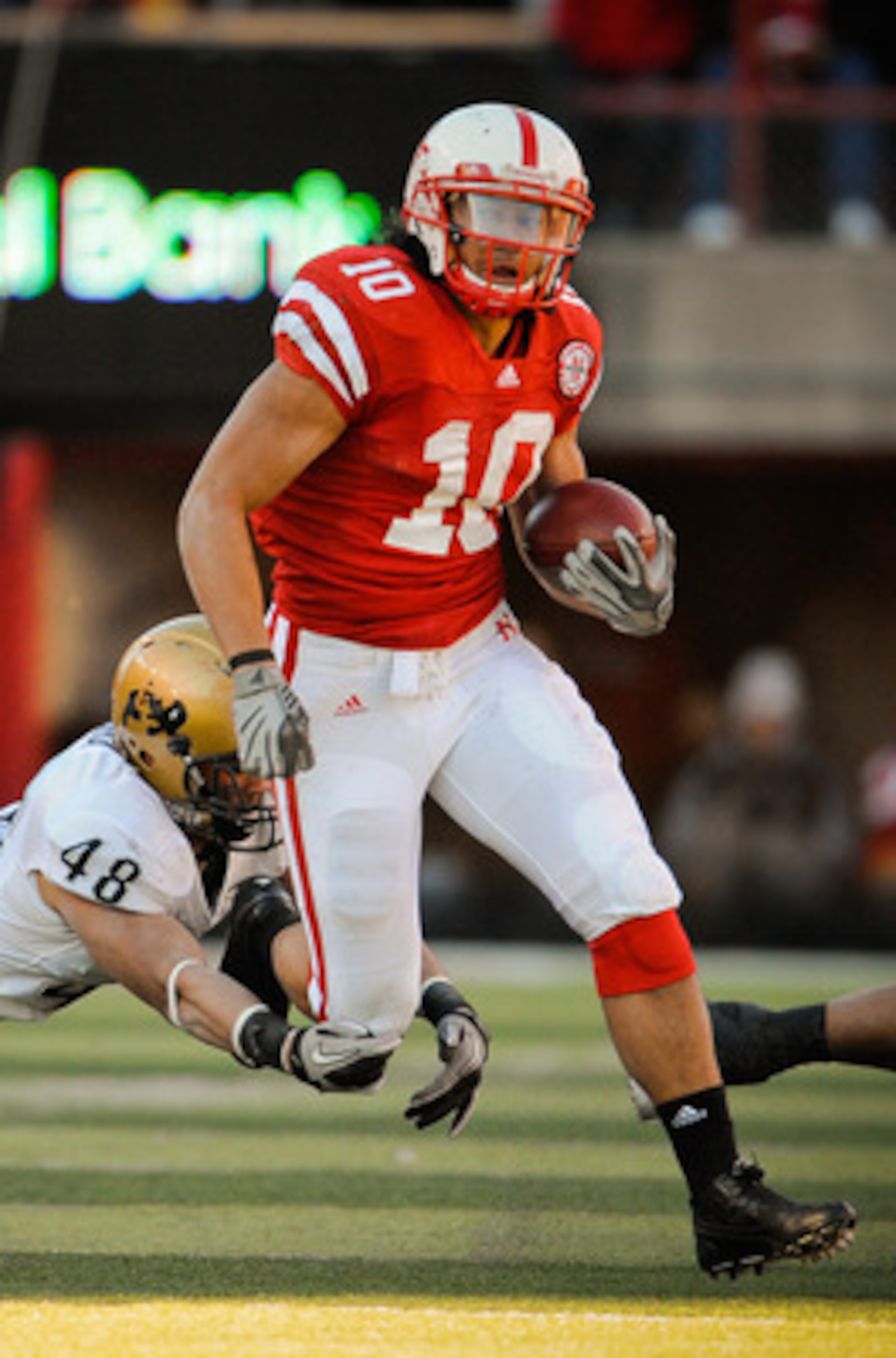 LINCOLN, NE - NOVEMBER 26: Roy Helu Jr. #10 of the Nebraska Cornhuskers runs past Liloa Nobriga #48 of the Colorado Buffaloes during the first half of their game at Memorial Stadium on November 26, 2010 in Lincoln, Nebraska. Nebraska defeated Colorado 45-