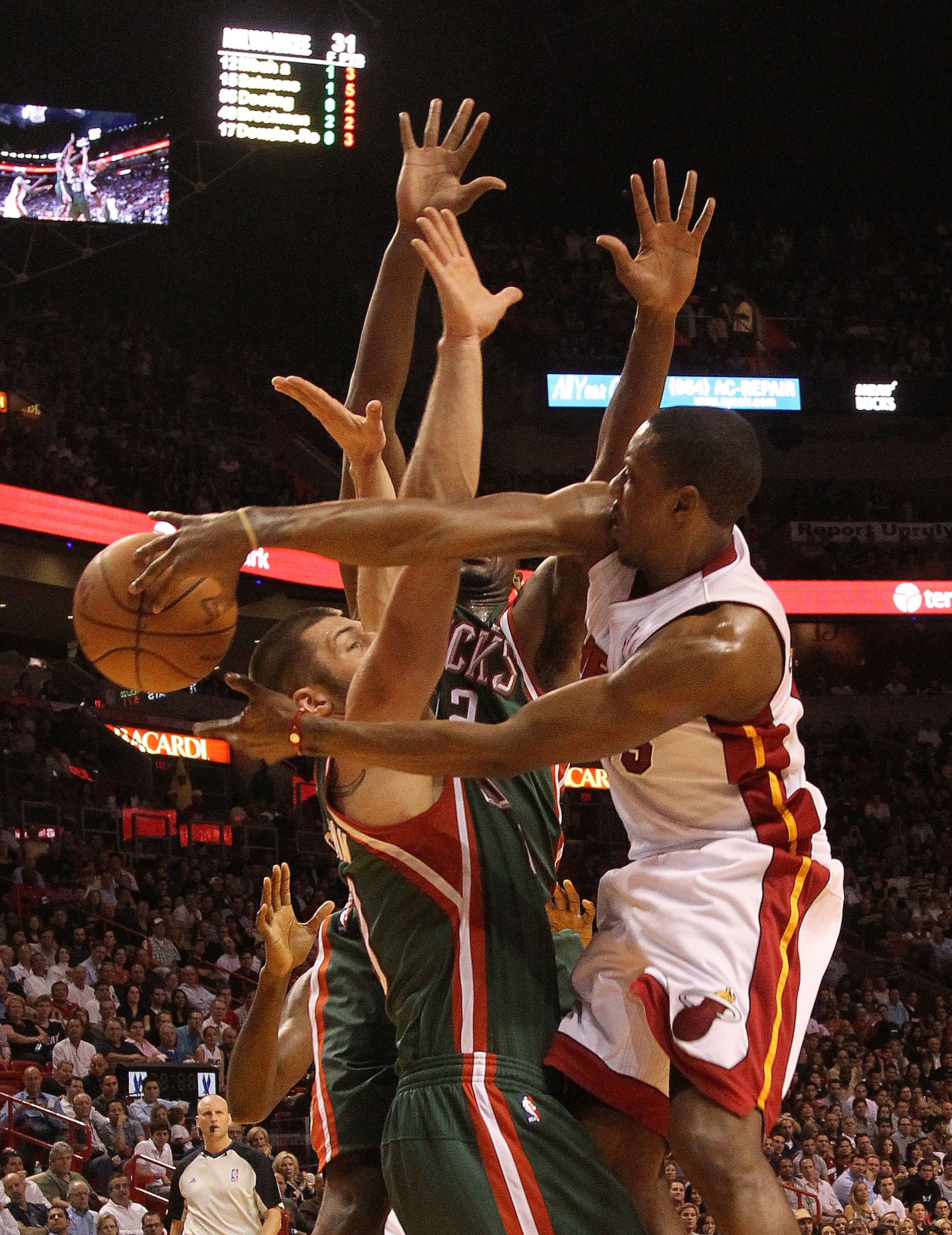 MIAMI, FL - JANUARY 04: Mario Chalmers #15 of the Miami Heat passes the ball over Jon Brockman #40 of the Milwaukee Bucks during a game at American Airlines Arena on January 4, 2011 in Miami, Florida. NOTE TO USER: User expressly acknowledges and agrees t
