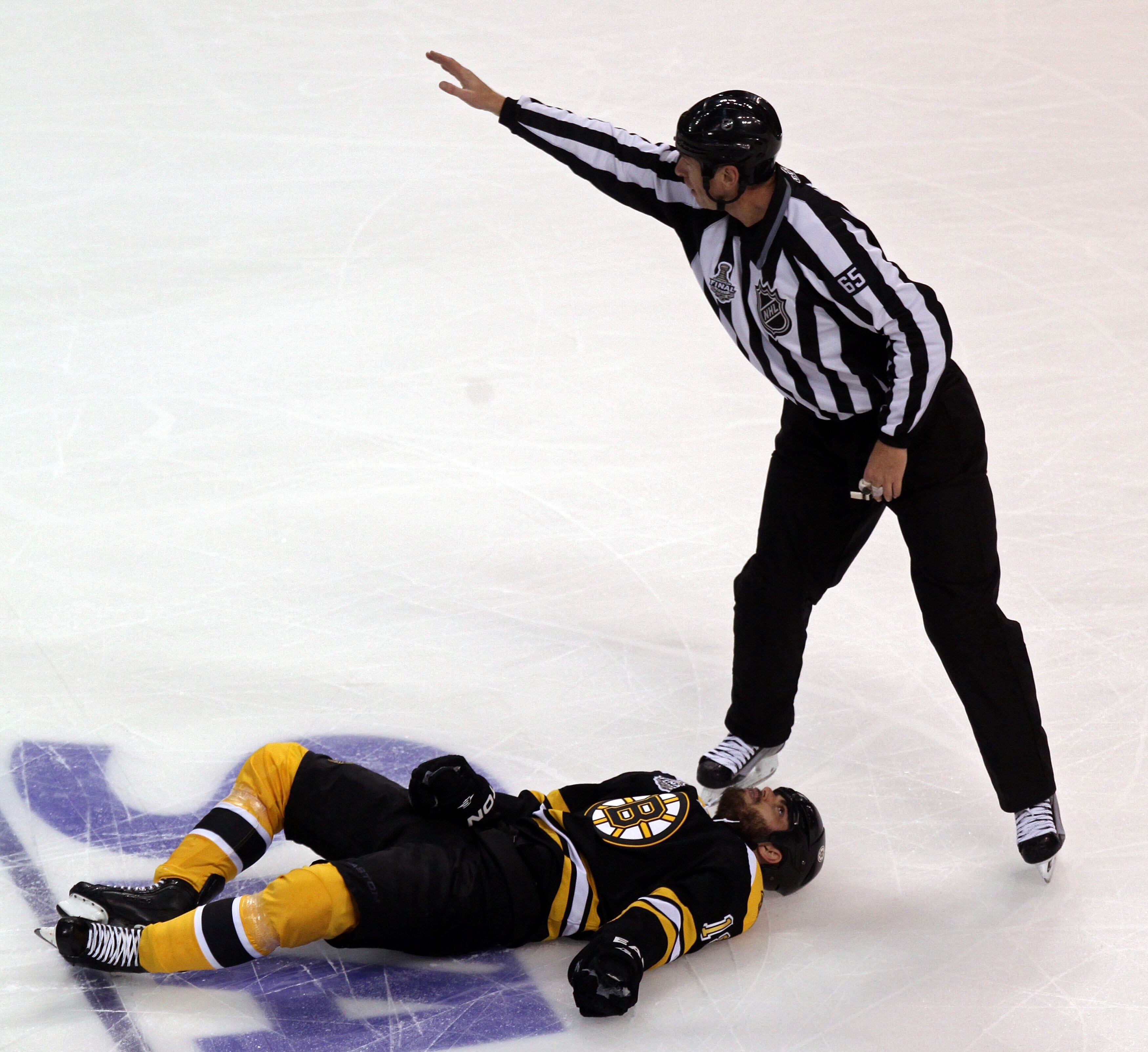 BOSTON, MA - JUNE 06:  Linesman Pierre Racicot #65 calls for assistance for Nathan Horton #18 of the Boston Bruins after being check by Aaron Rome (not pictured) #29 of the Vancouver Canucks during Game Three of the 2011 NHL Stanley Cup Final at TD Garden