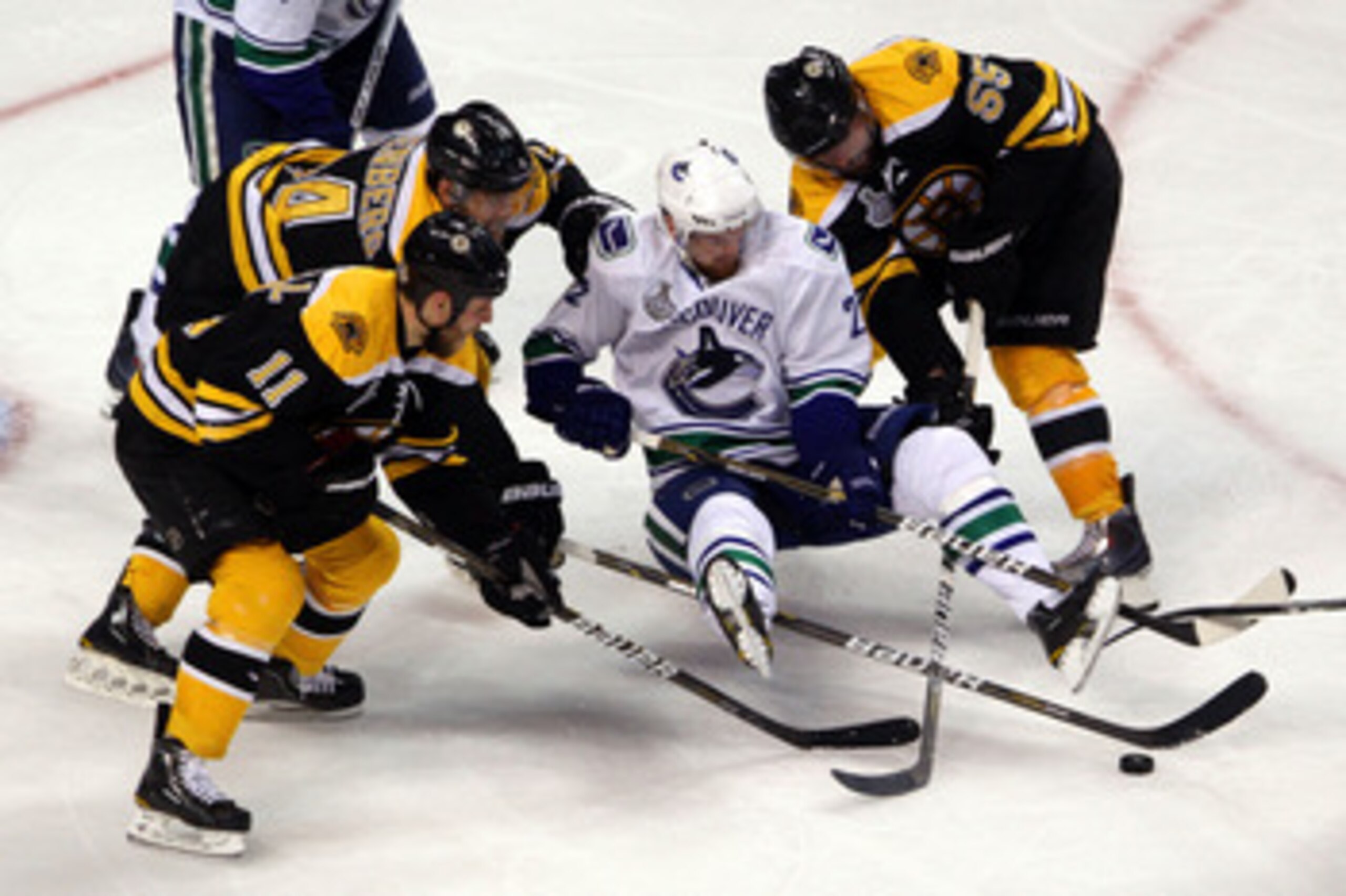 BOSTON, MA - JUNE 06:  Daniel Sedin #22 of the Vancouver Canucks loses his balance while handling the puck against Johnny Boychuk #55, Gregory Campbell #11 and Dennis Seidenberg #44 of the Boston Bruins during Game Three of the 2011 NHL Stanley Cup Final 